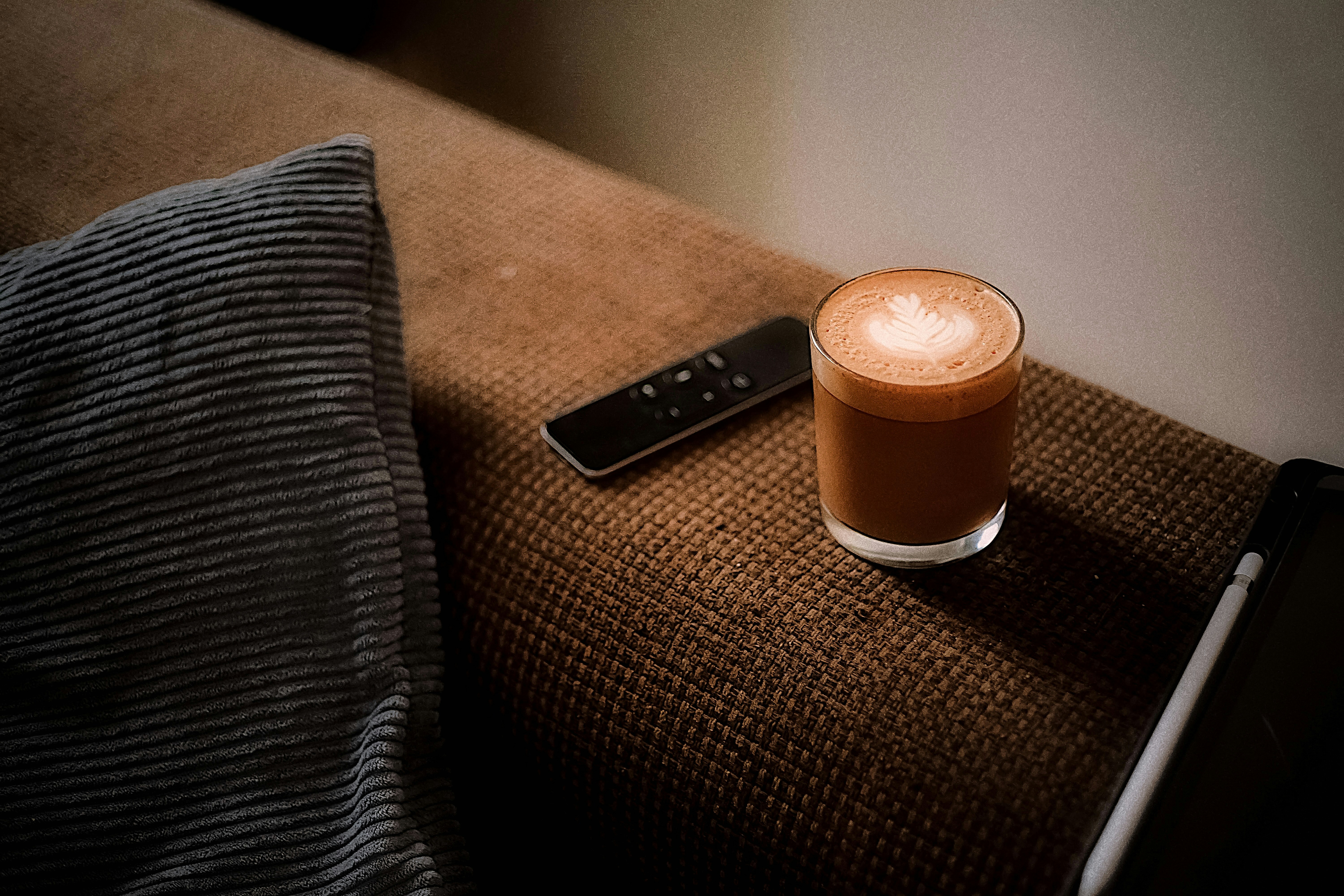 Un latte con latte art accanto a un telecomando.