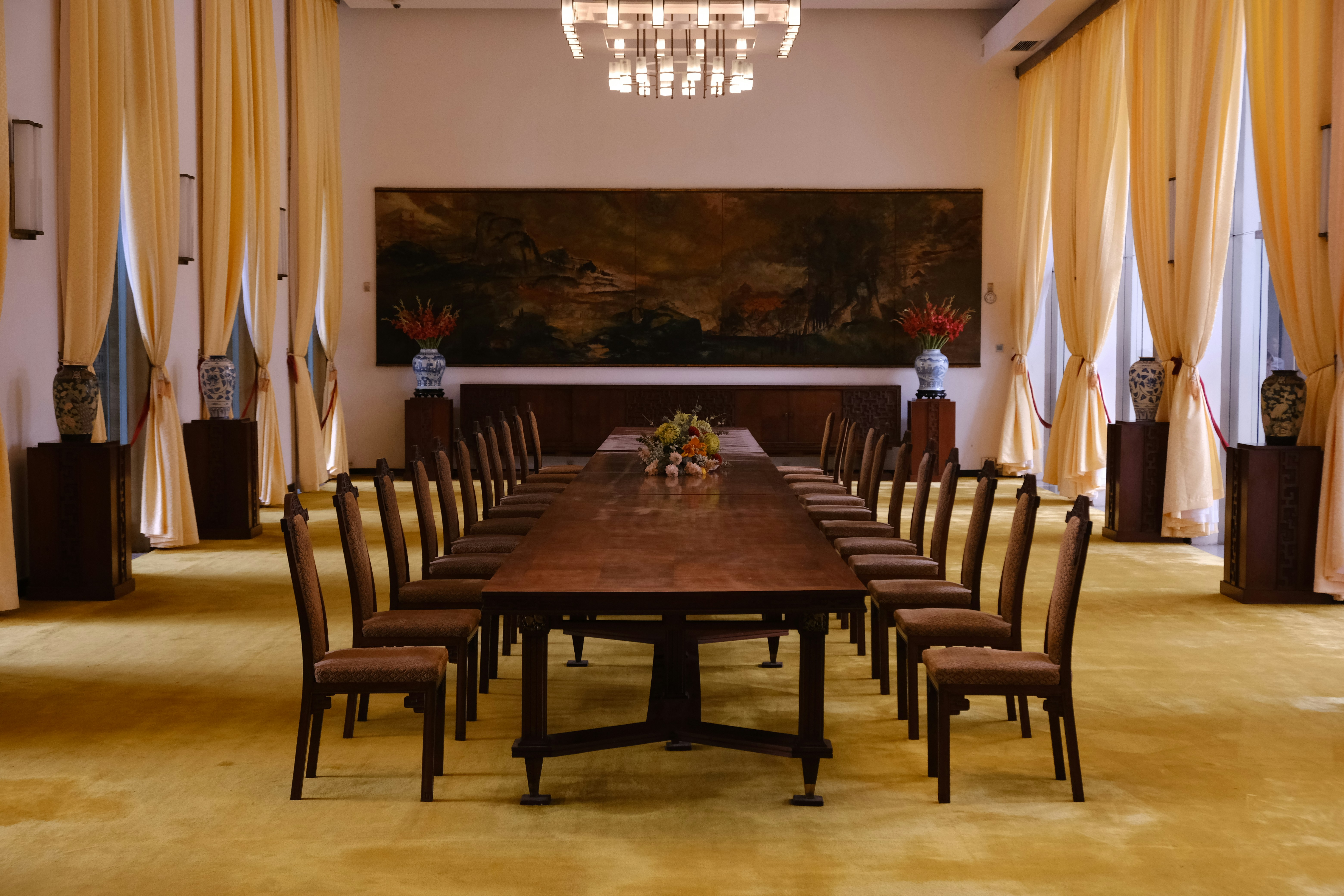 Long wooden table with chairs in a formal room.