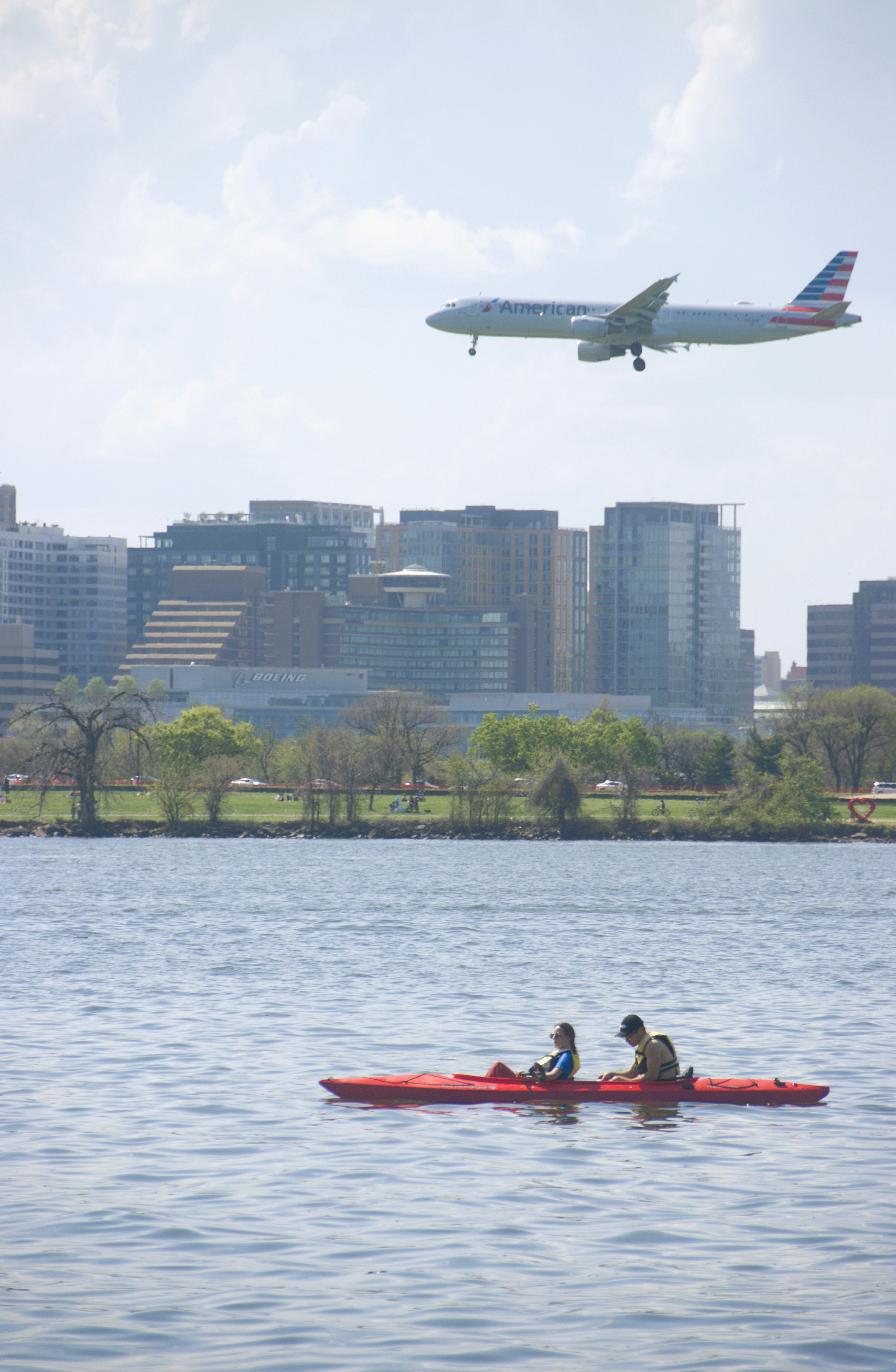 Two people kayak on water with airplane overhead
