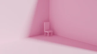 A single pink chair in a minimalist pink room