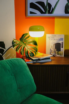 Green chair next to a lamp and books.