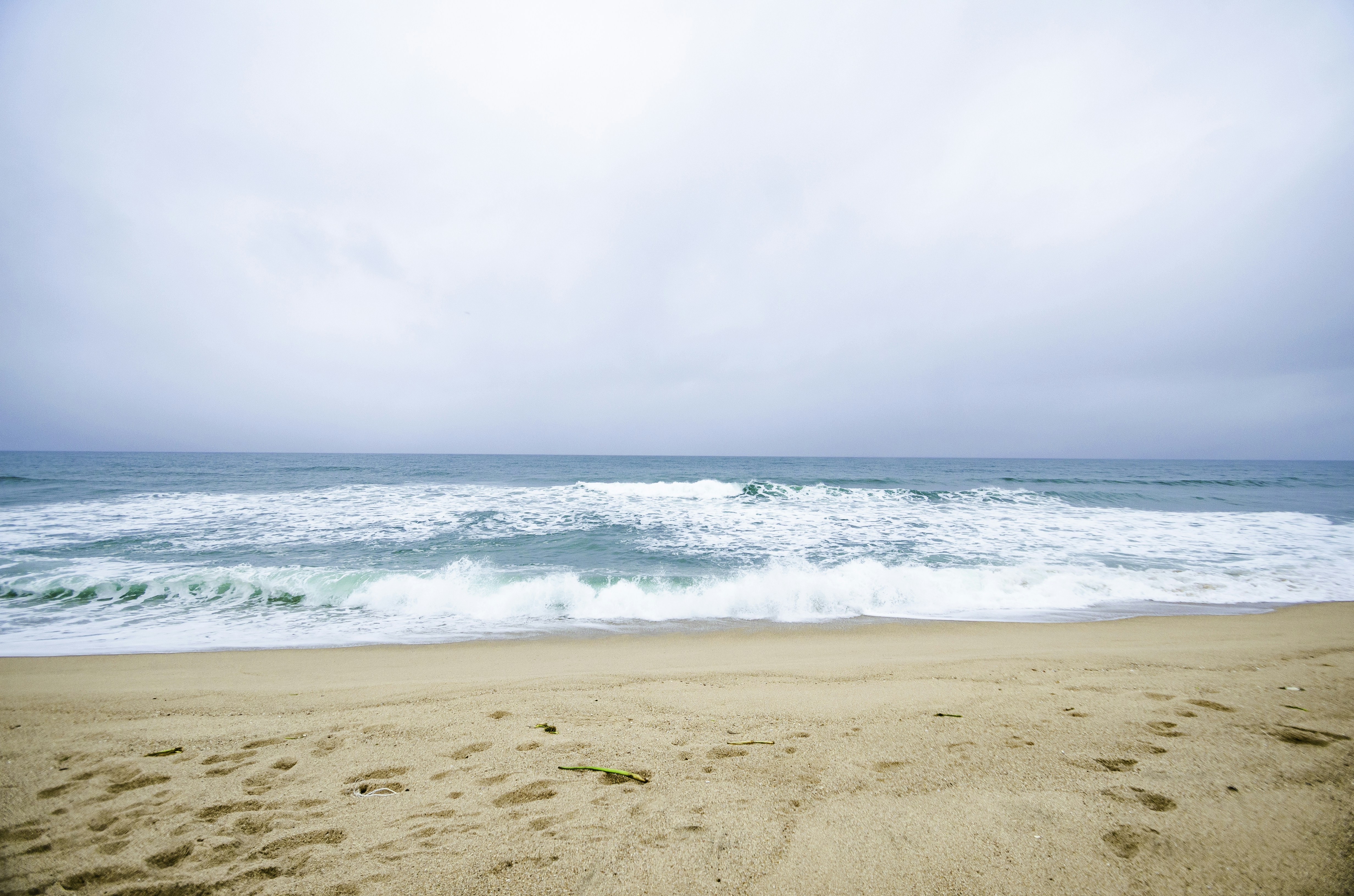 Spiaggia di sabbia con onde che si infrangono sotto un cielo nuvoloso