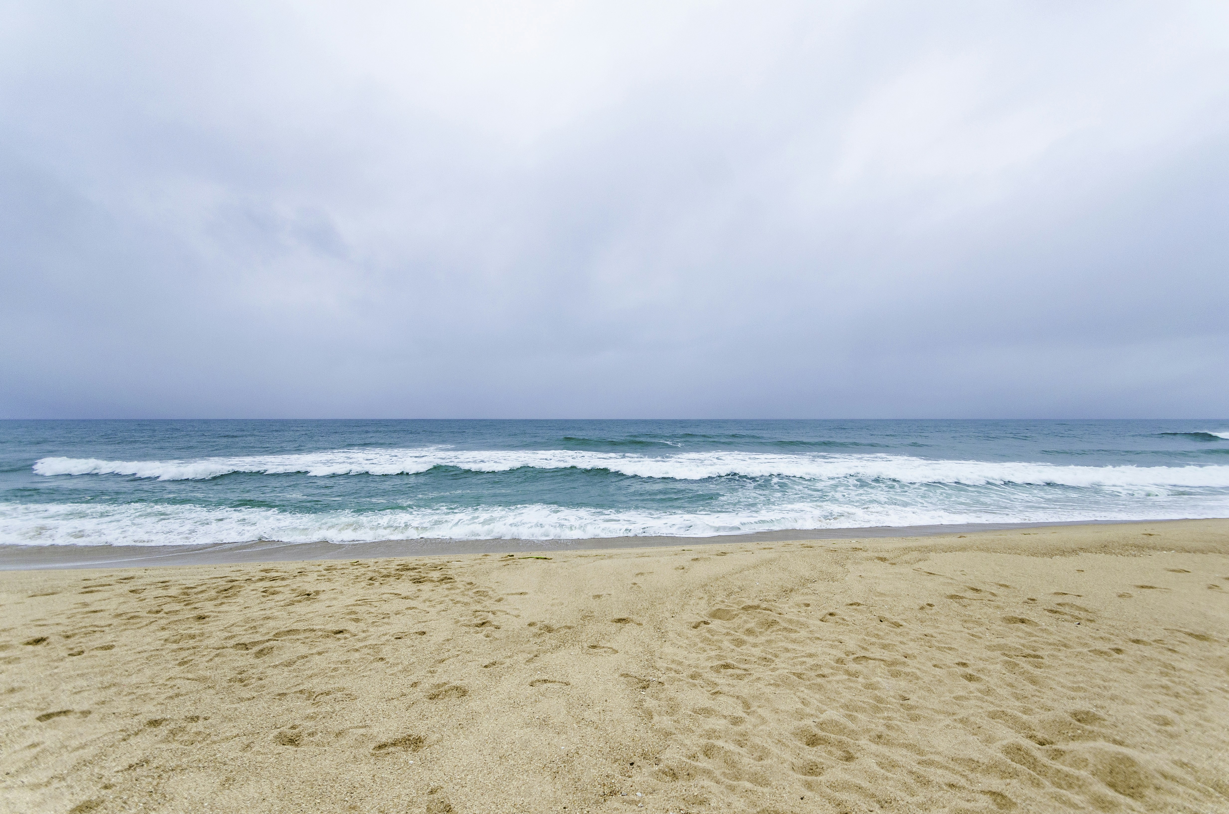 Spiaggia sabbiosa con onde leggere sotto un cielo nuvoloso