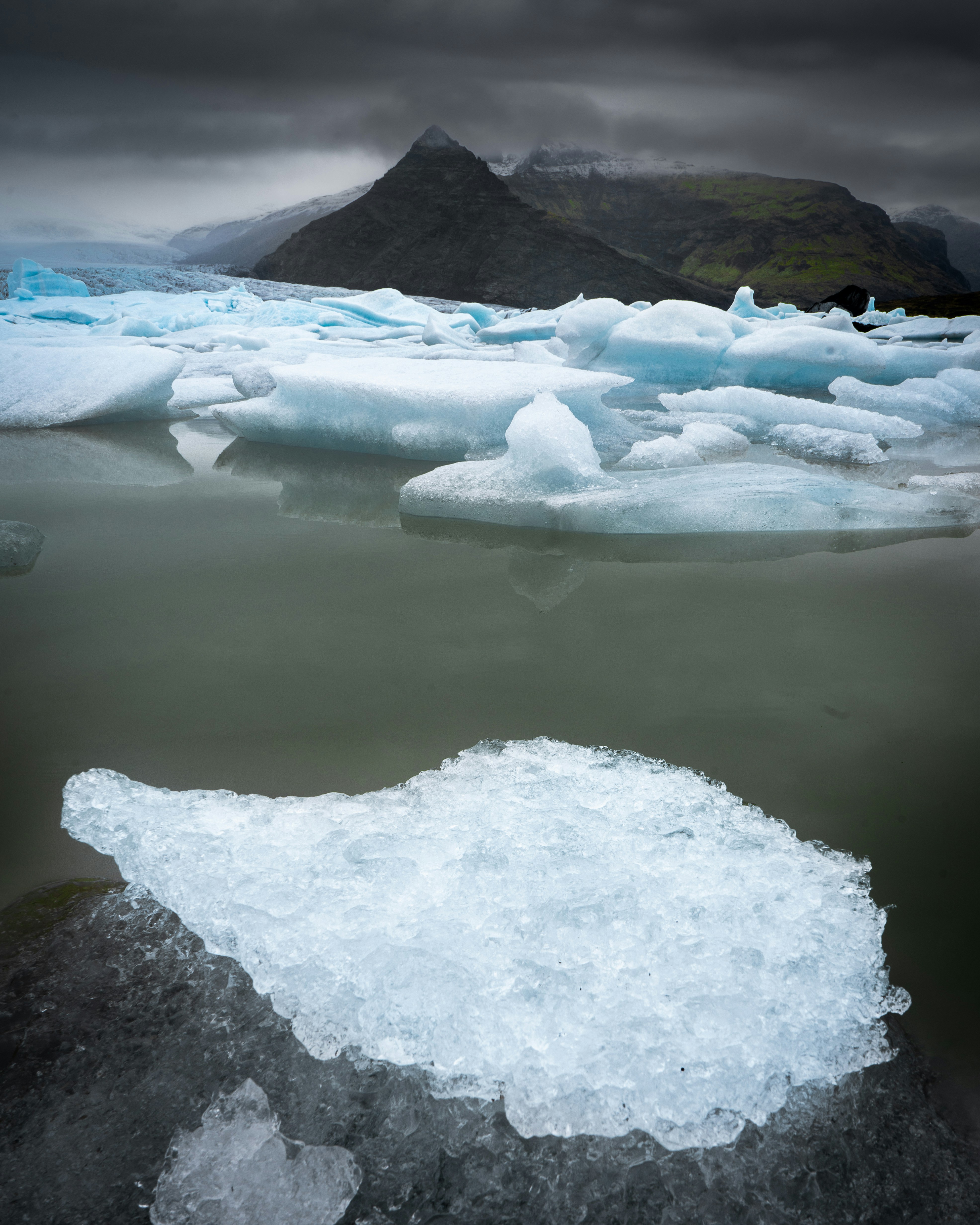 Floating icebergs in a dark, moody glacial lake.