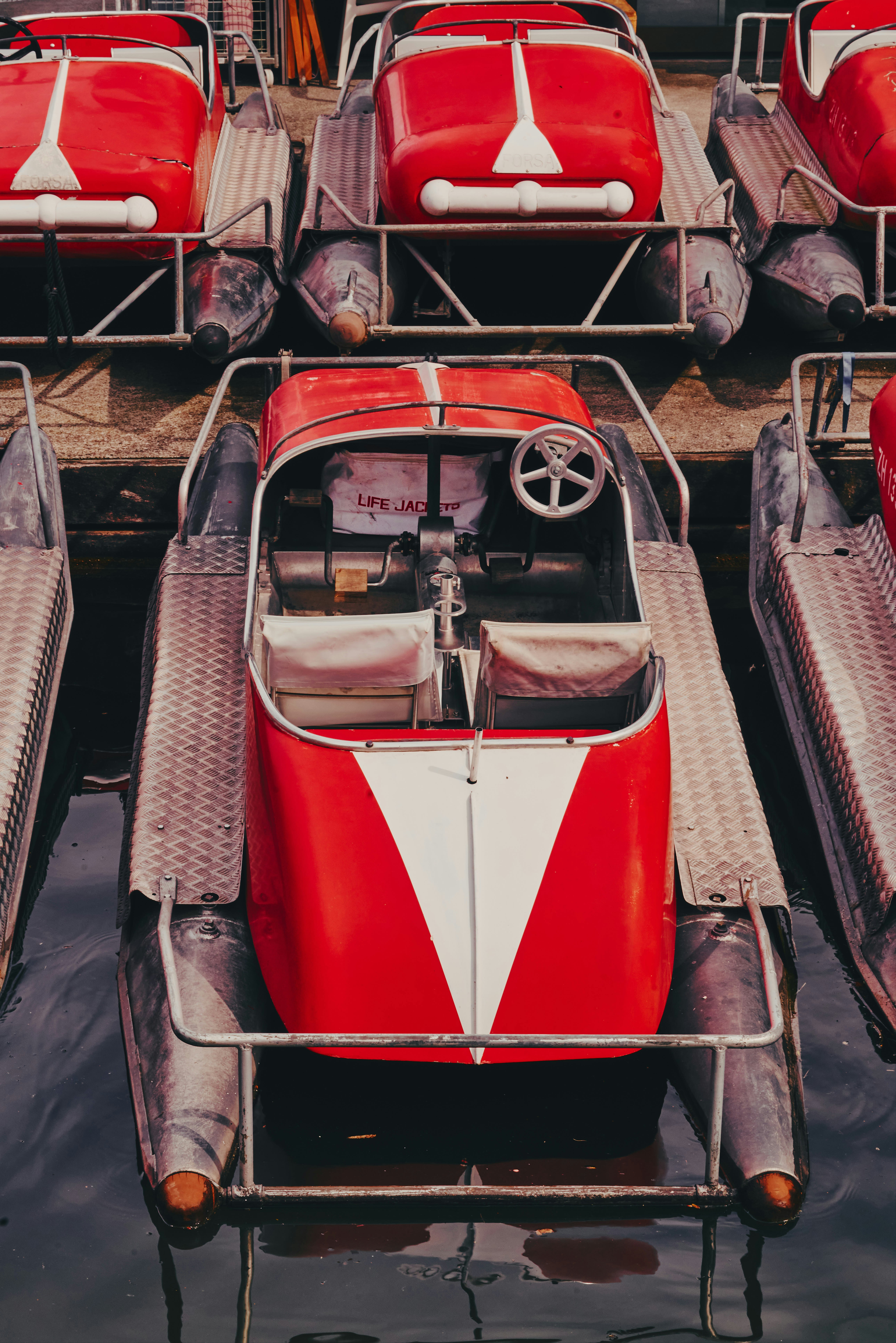 Several red pedal boats docked on the water