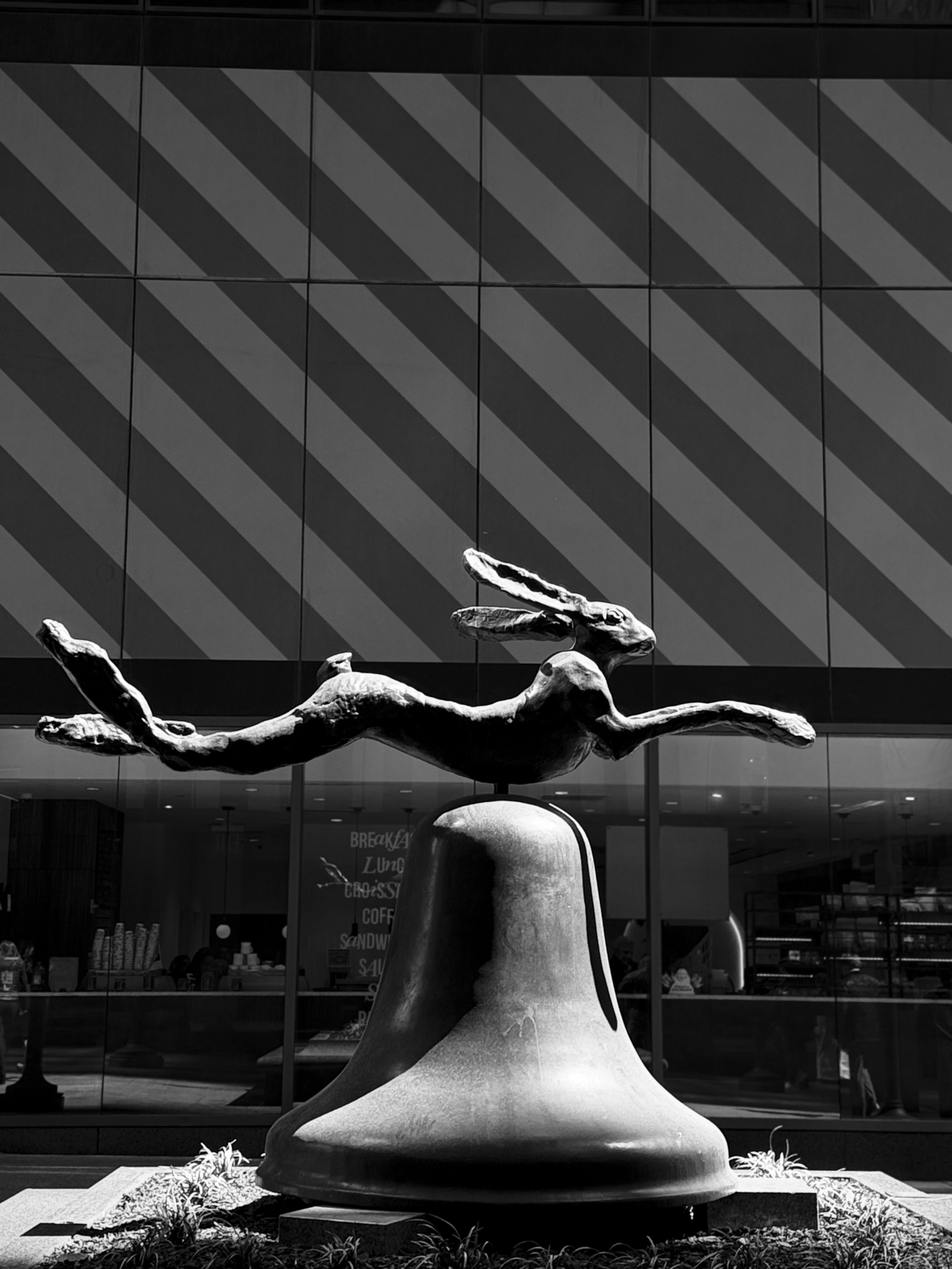A bronze sculpture of a running rabbit on a bell.