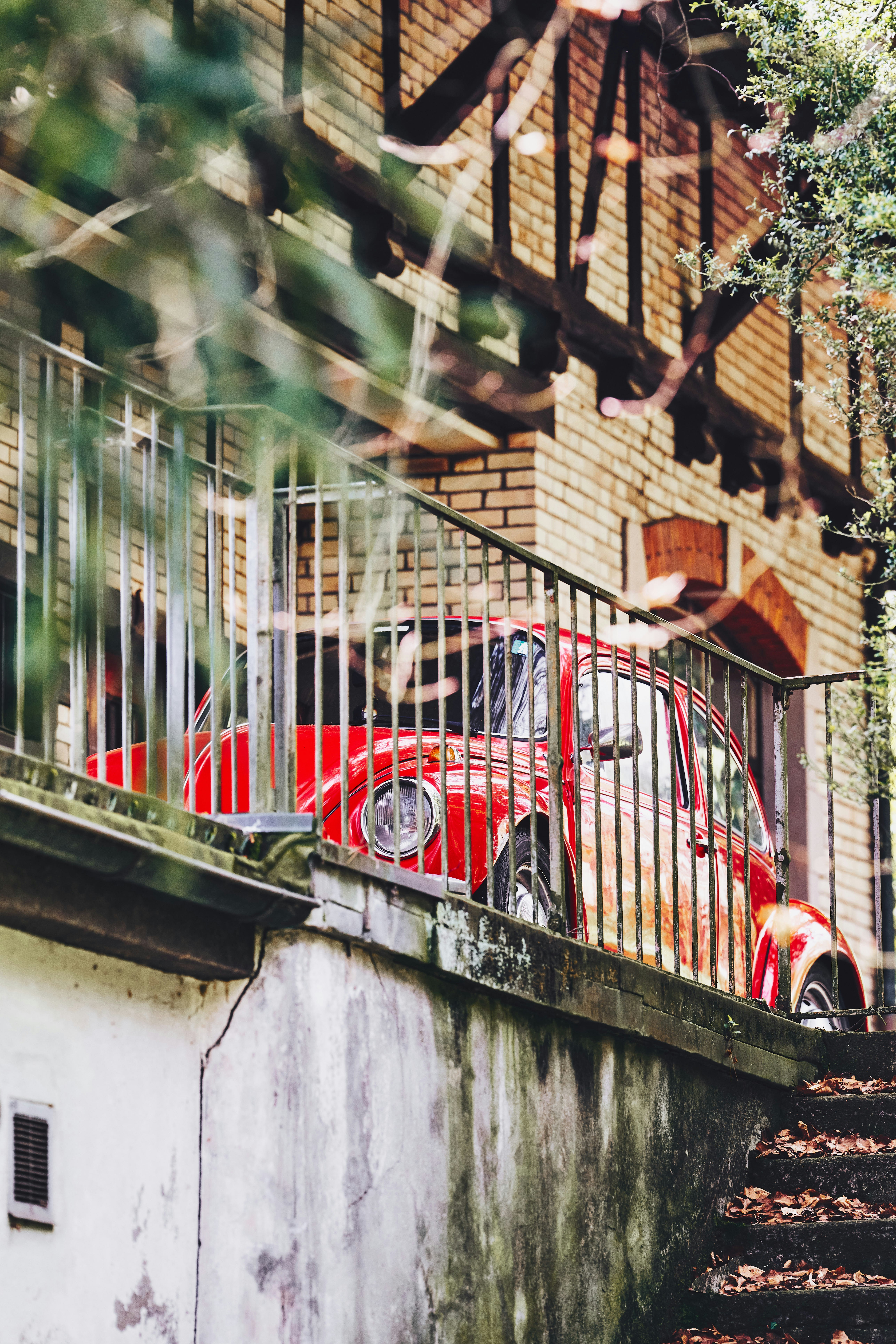 Red vintage car parked near a brick building.