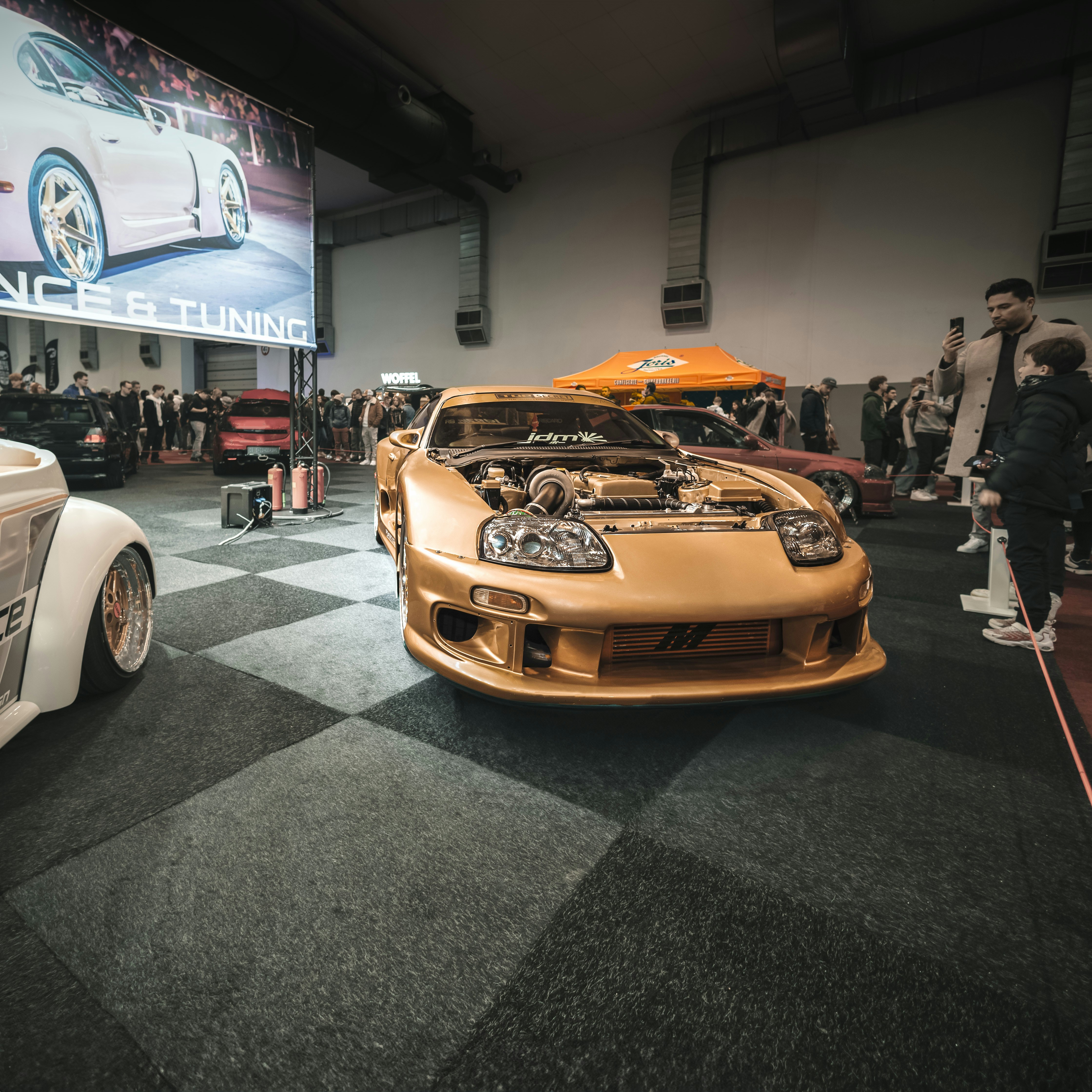 Golden sports car displayed at an indoor event.