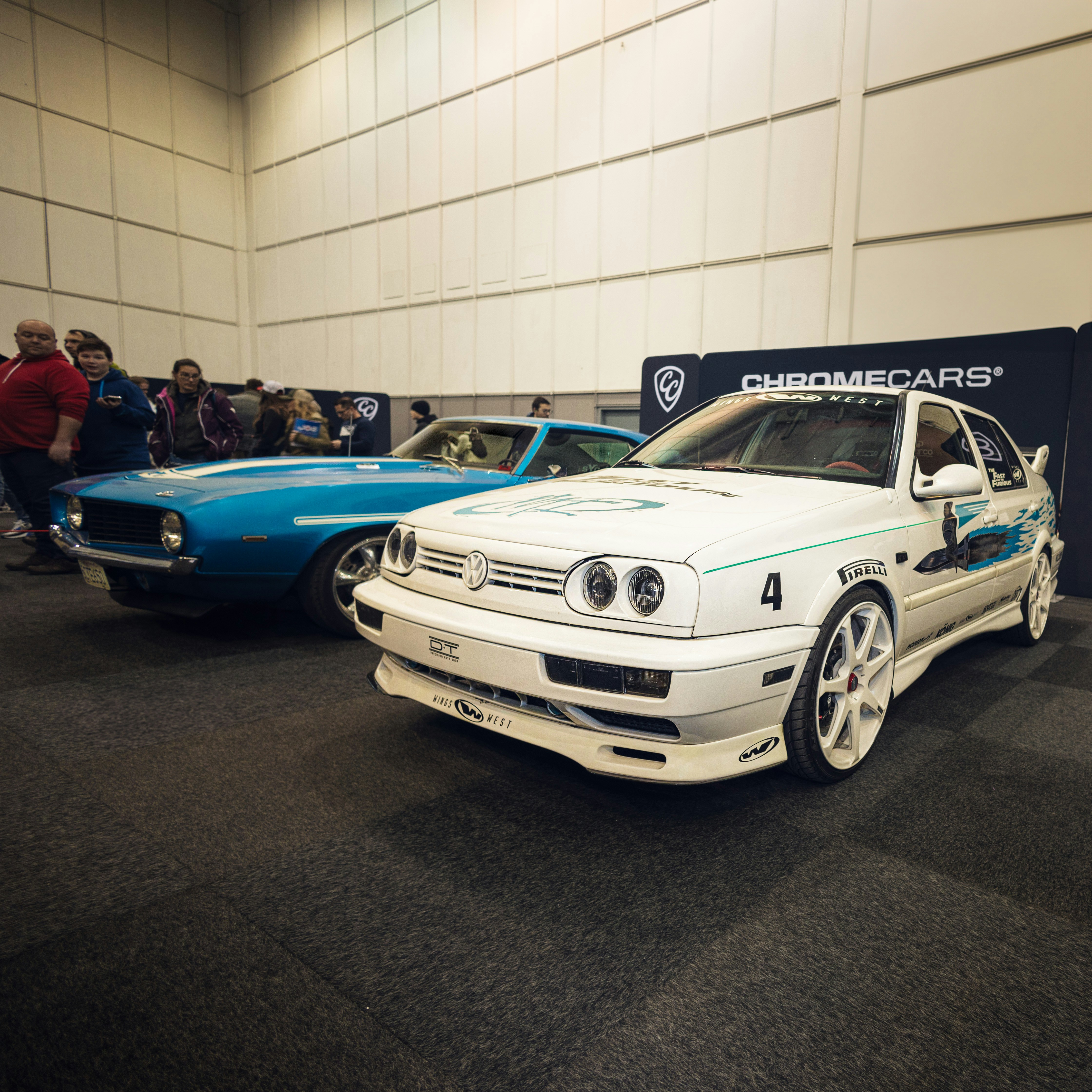 White volkswagen and blue classic car displayed indoors