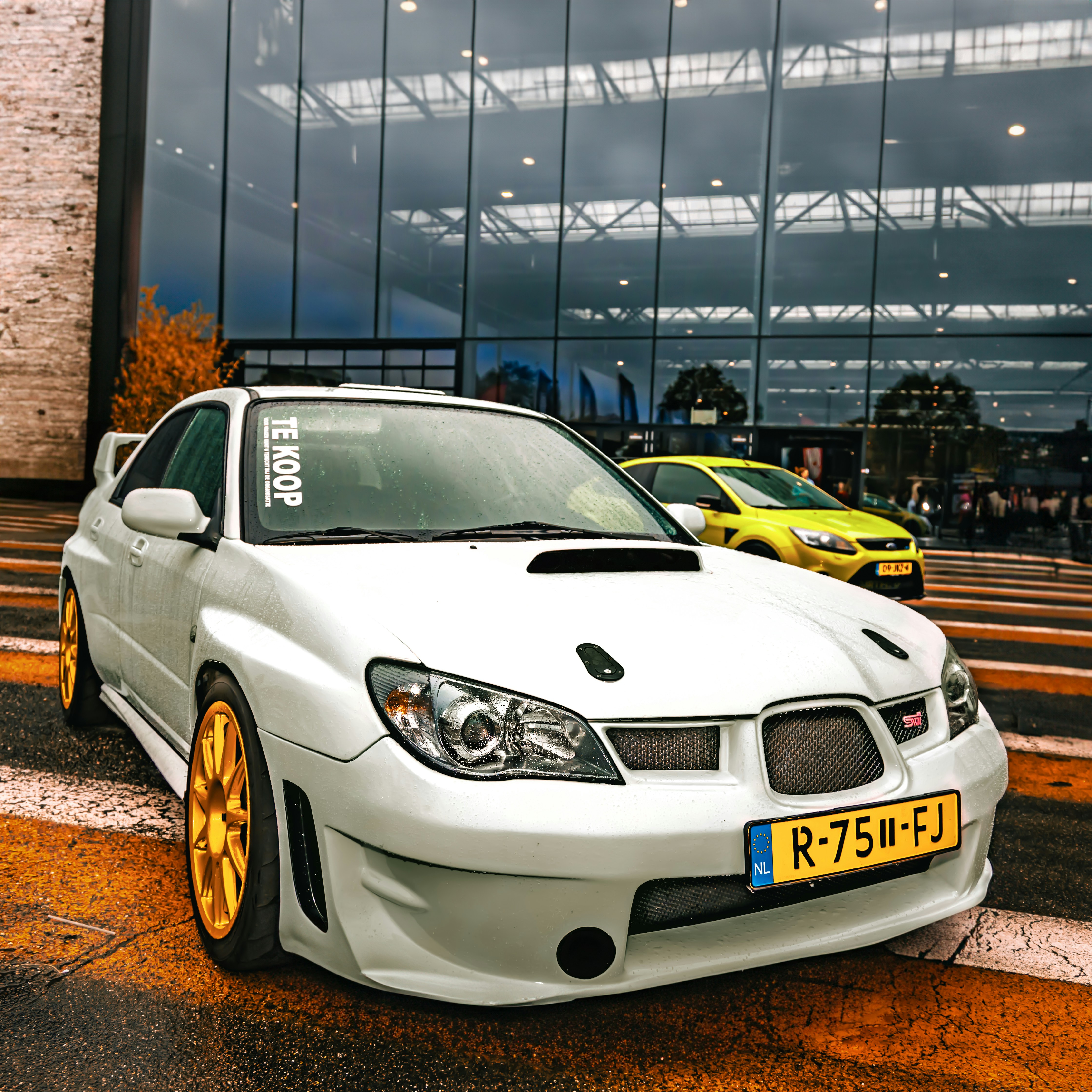 White subaru wrx sti with gold wheels parked.