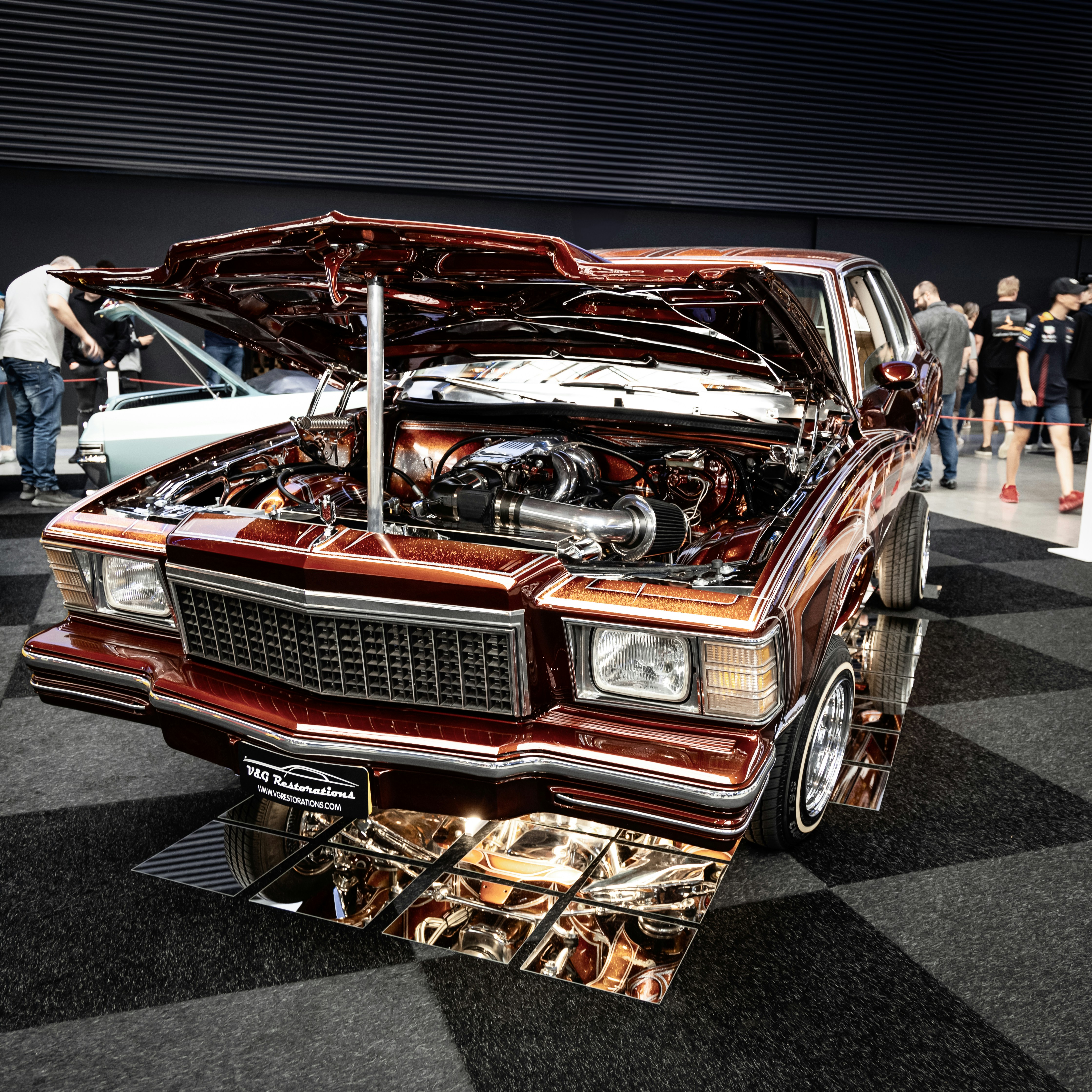 Customized classic car with open hood and chrome details.