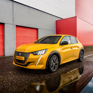 Yellow peugeot 208 parked outside modern building