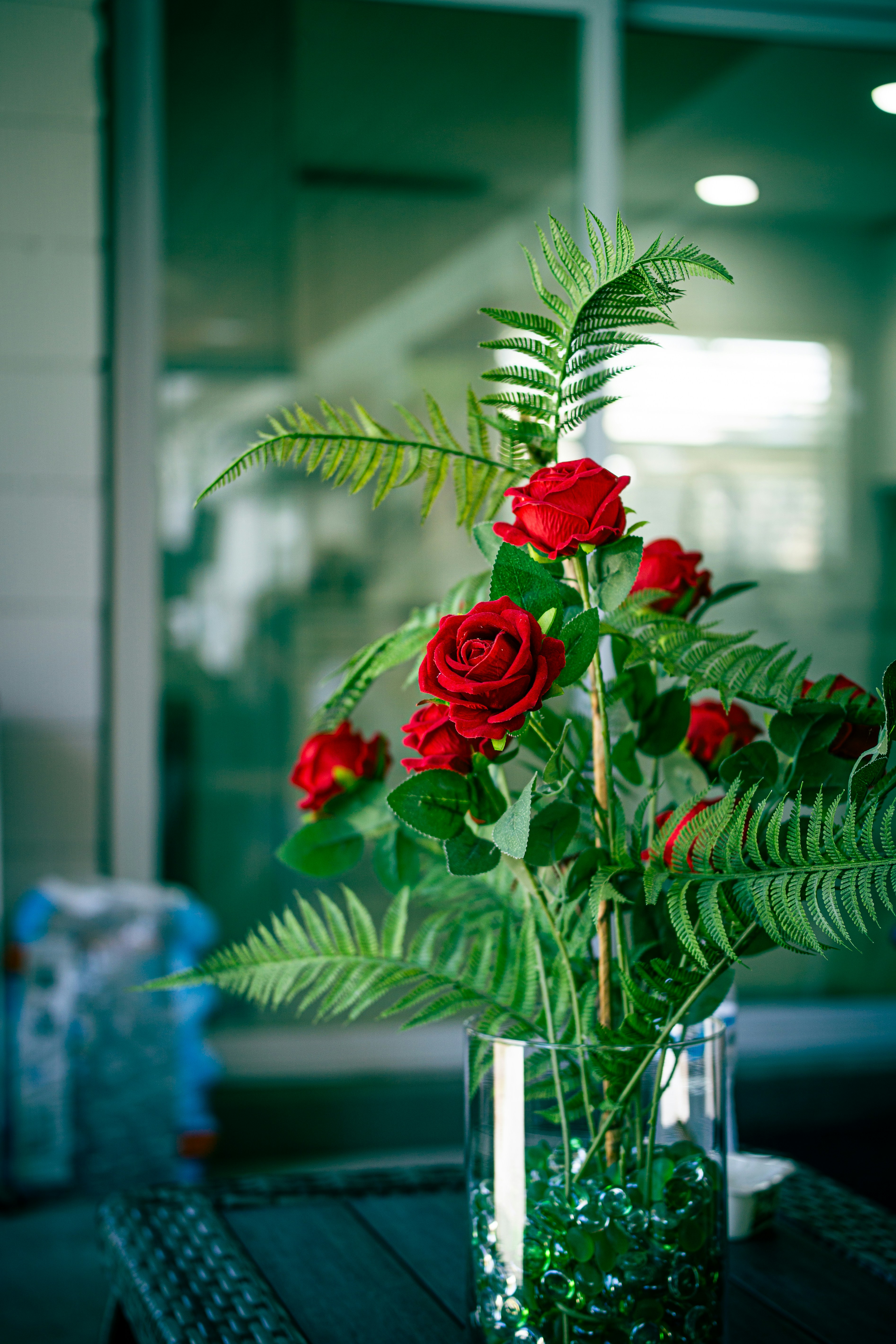Red roses and ferns in a glass vase.