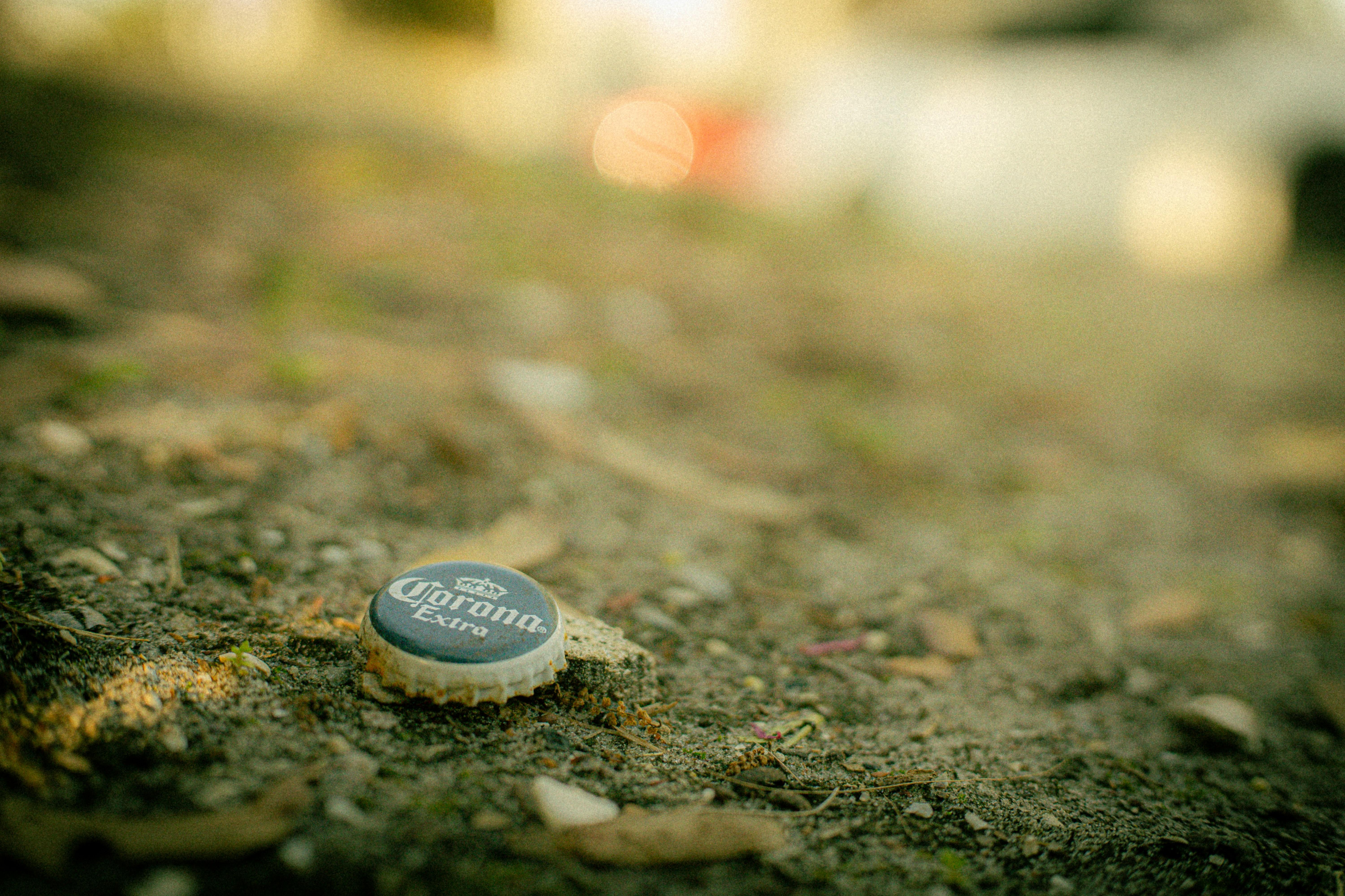 A corona beer bottle cap lies on the ground.