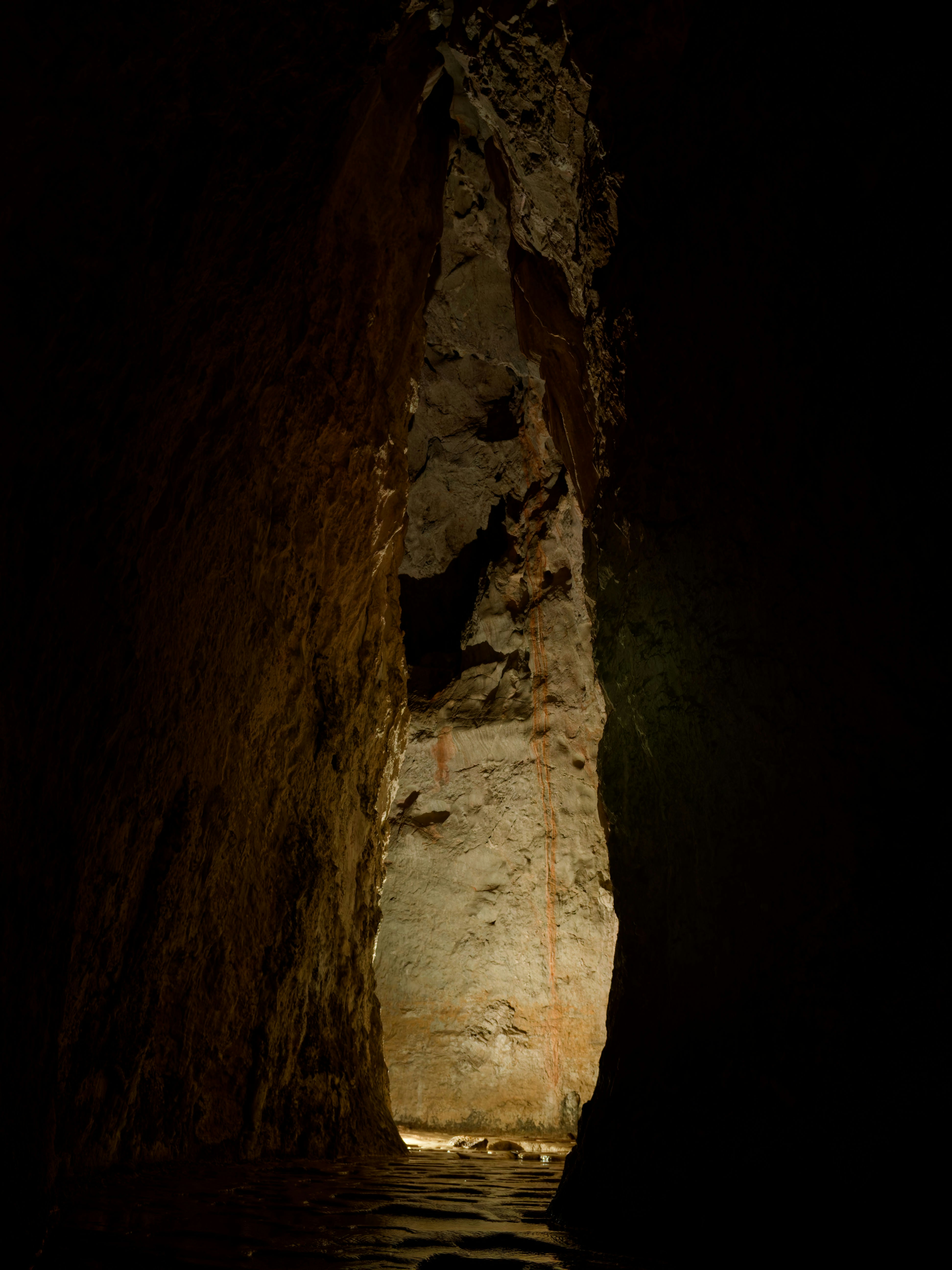 Un pasaje estrecho en una cueva con agua en el fondo.