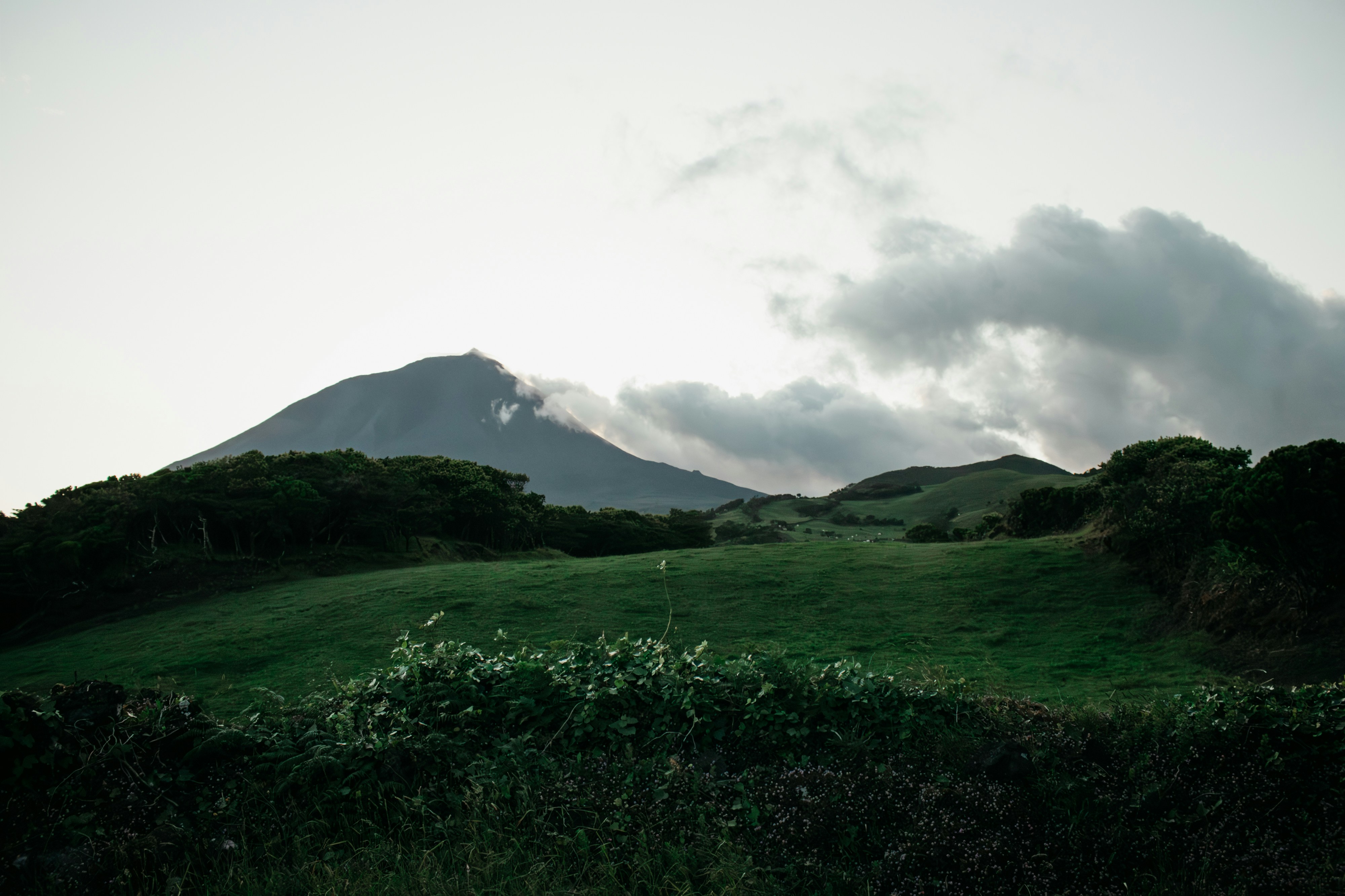 Mountain peak shrouded in clouds over green hills