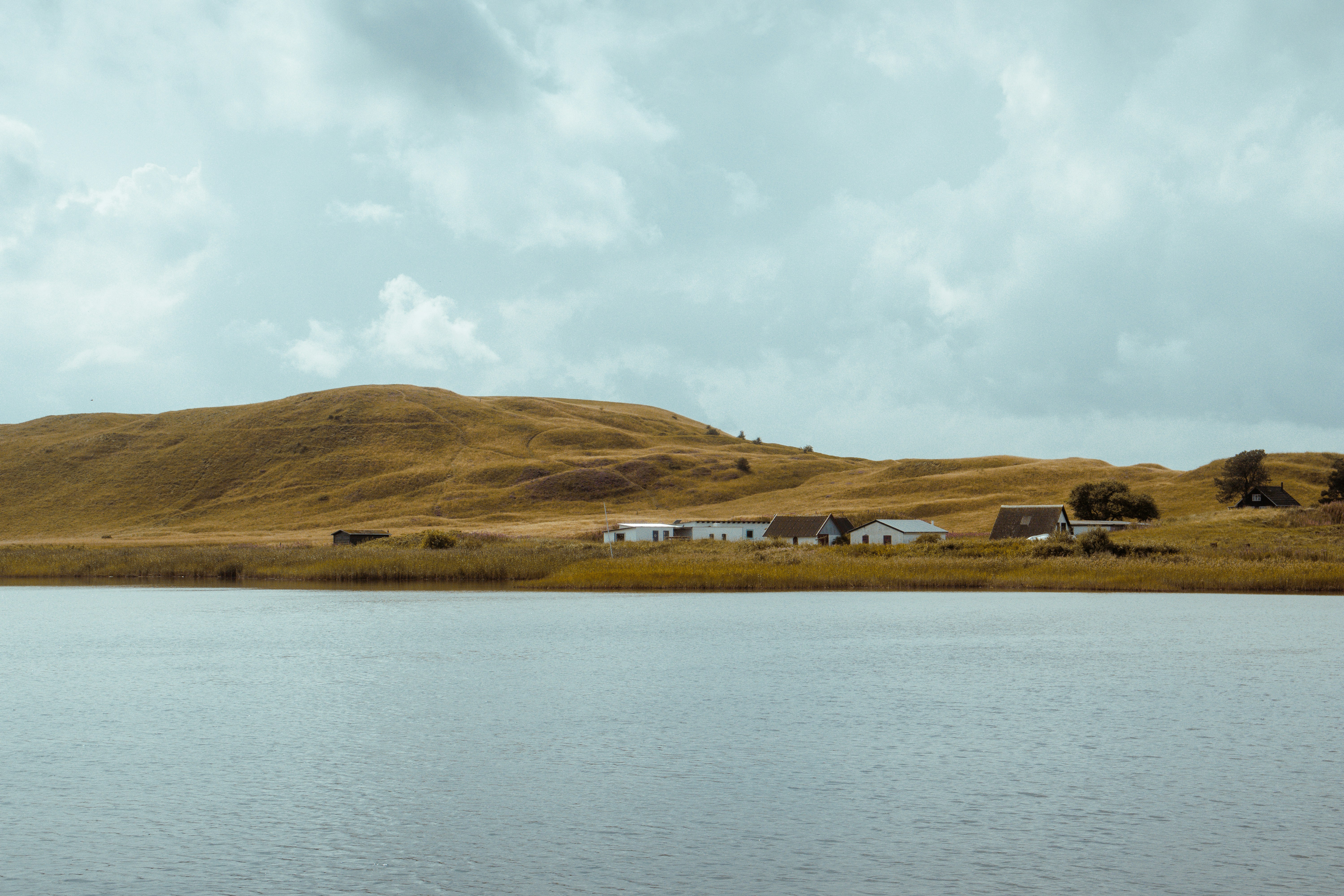 Pequeño pueblo enclavado junto a un lago tranquilo y colinas onduladas.