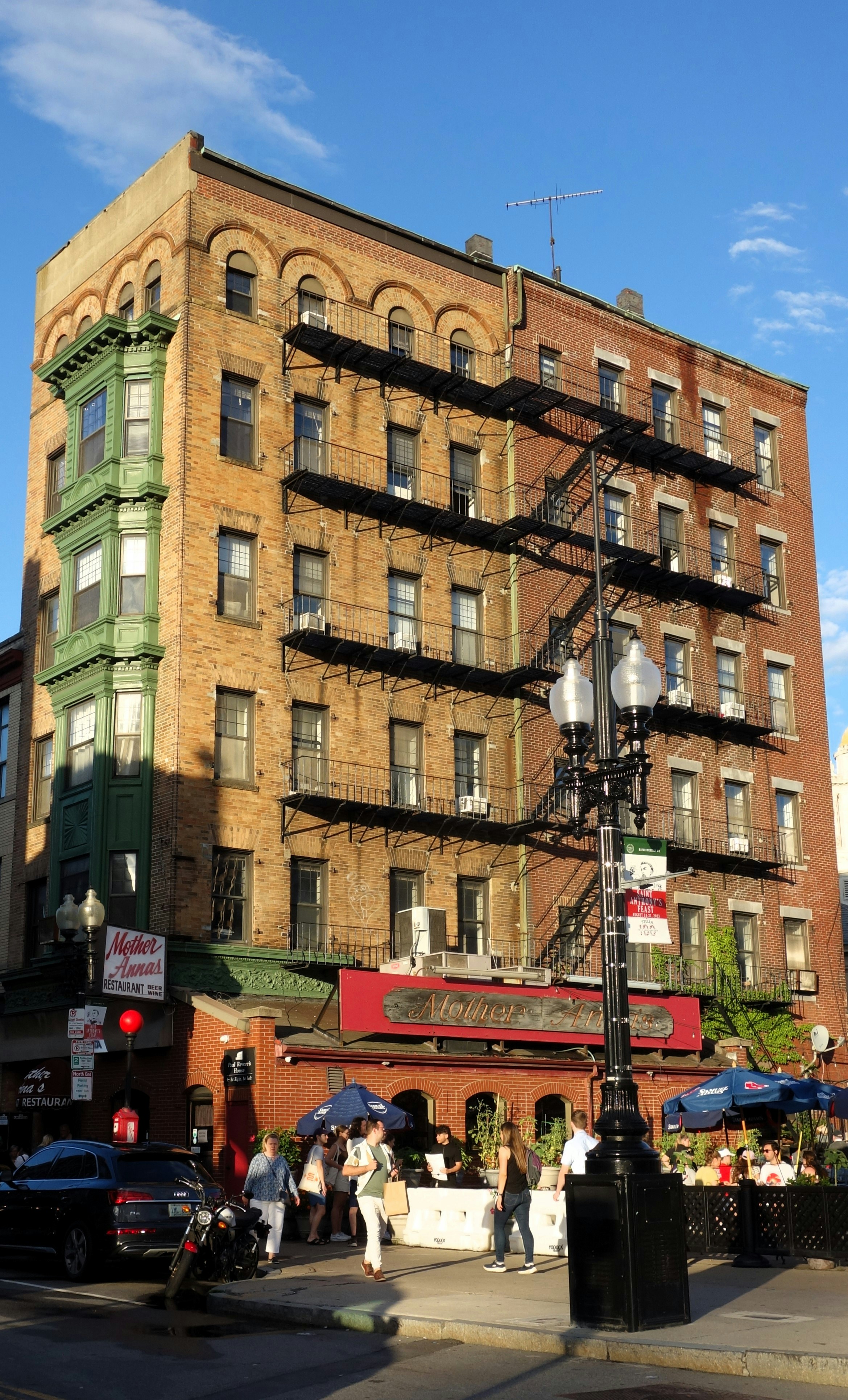 Brick building with green bay window and fire escape.