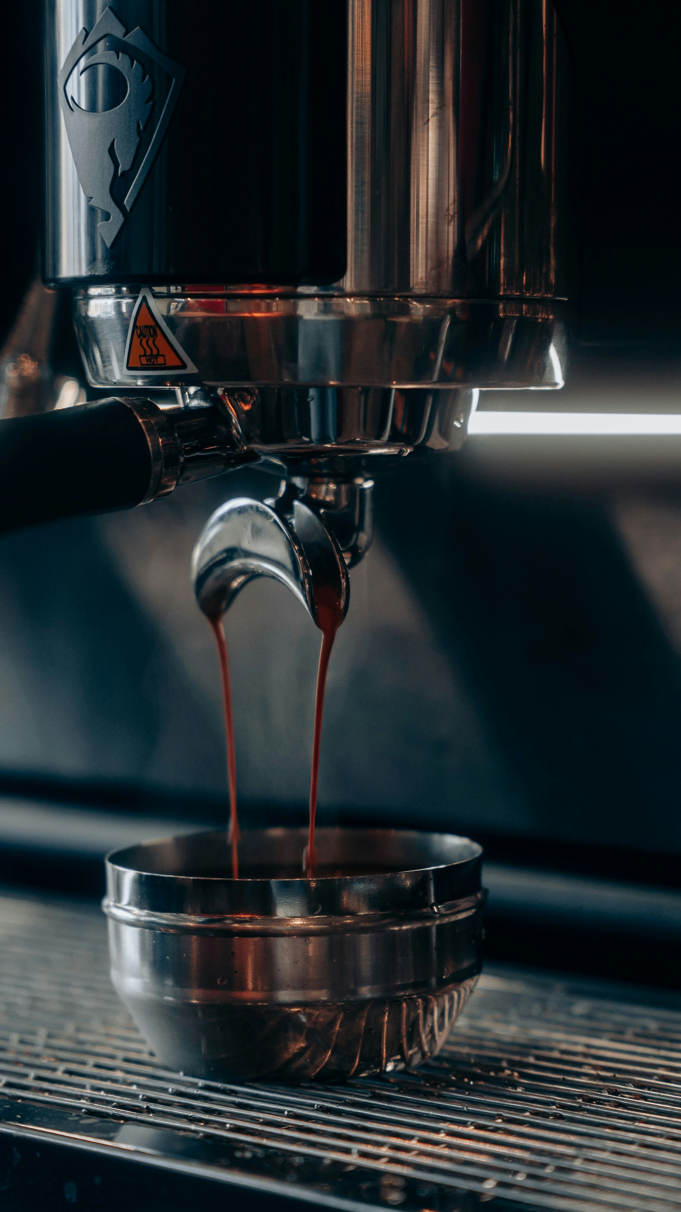 Espresso vertido en una taza metálica de la máquina