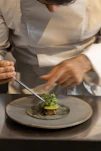Chef carefully plating a gourmet dish with tweezers.