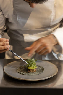 Chef carefully plating a gourmet dish with tweezers.