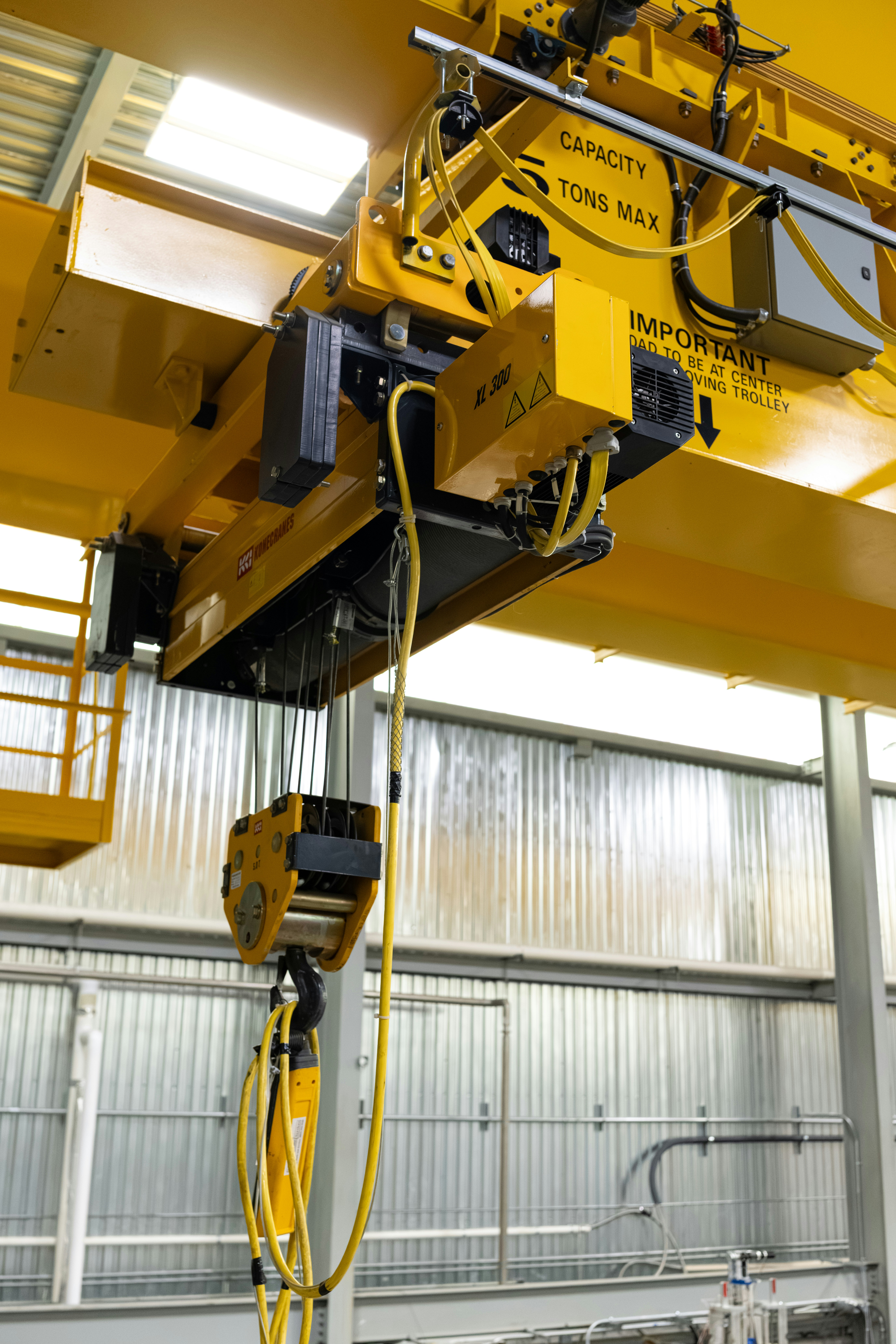 Yellow industrial overhead crane with hoist and cables