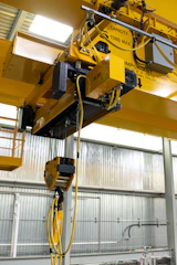 Yellow industrial overhead crane with hoist and cables