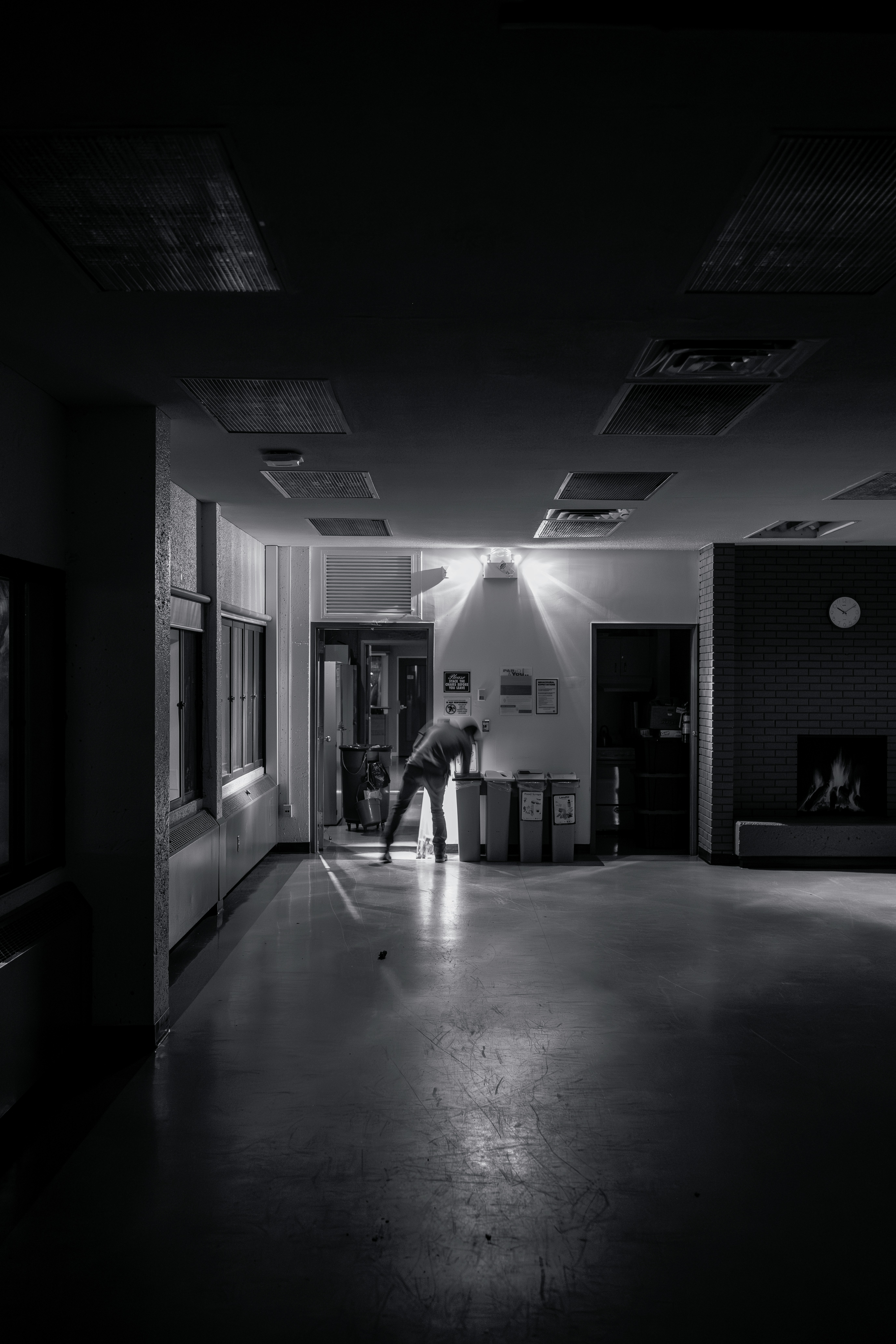 A person bends over in a dimly lit hallway.