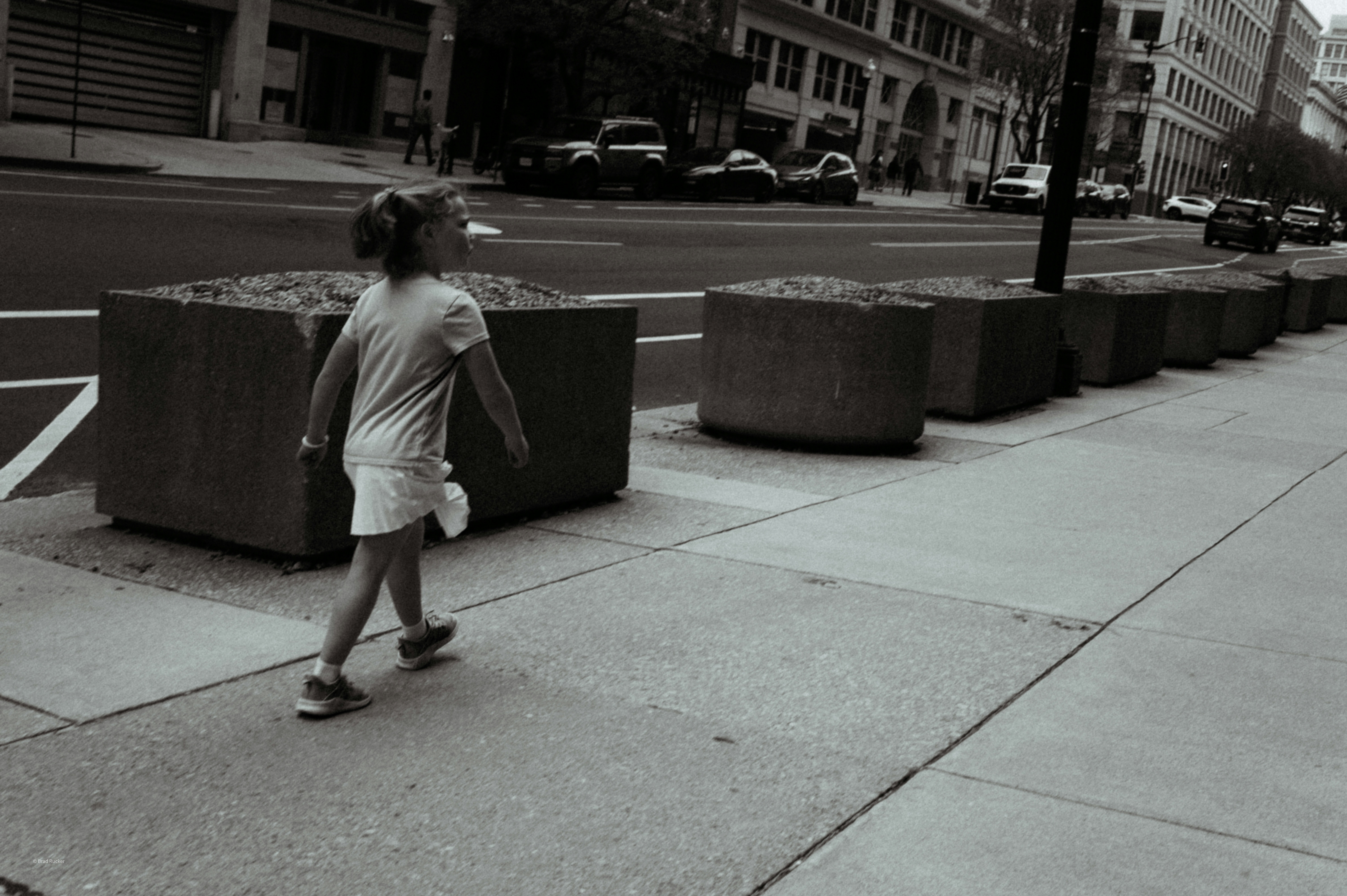 A young girl walks along a city sidewalk.