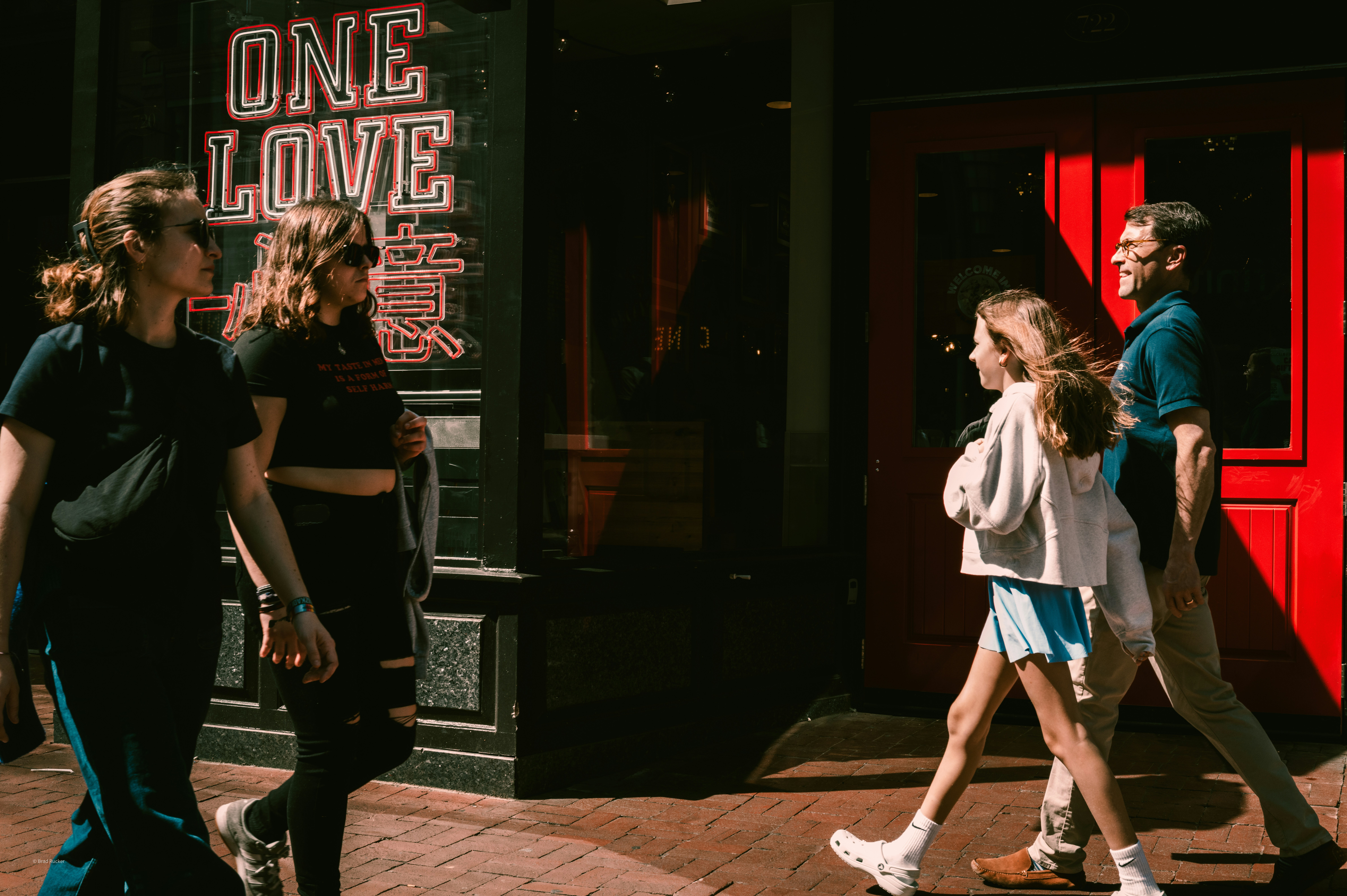People walking on a city sidewalk near a red door.