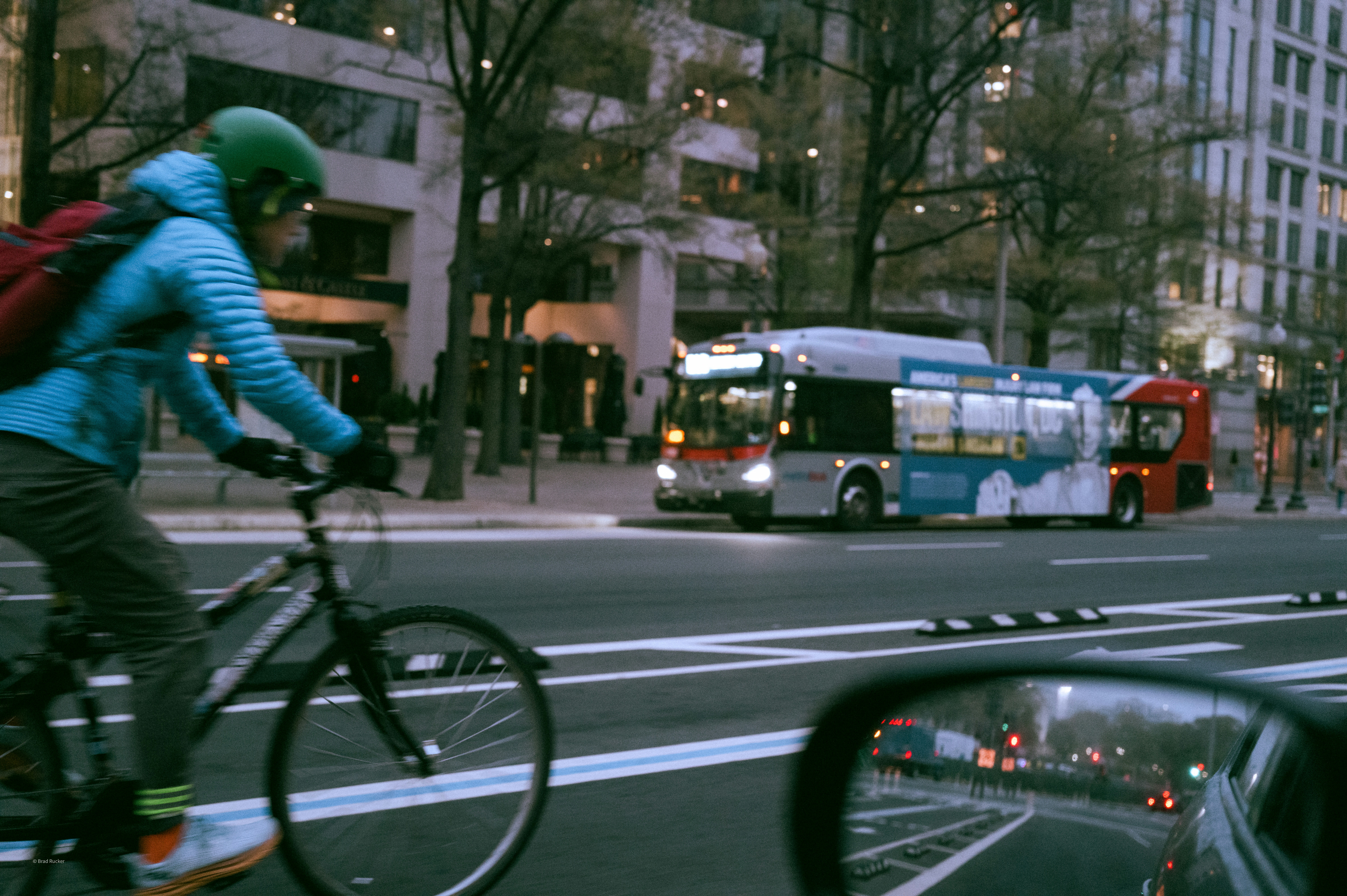 Cyclist and bus on city street at dusk