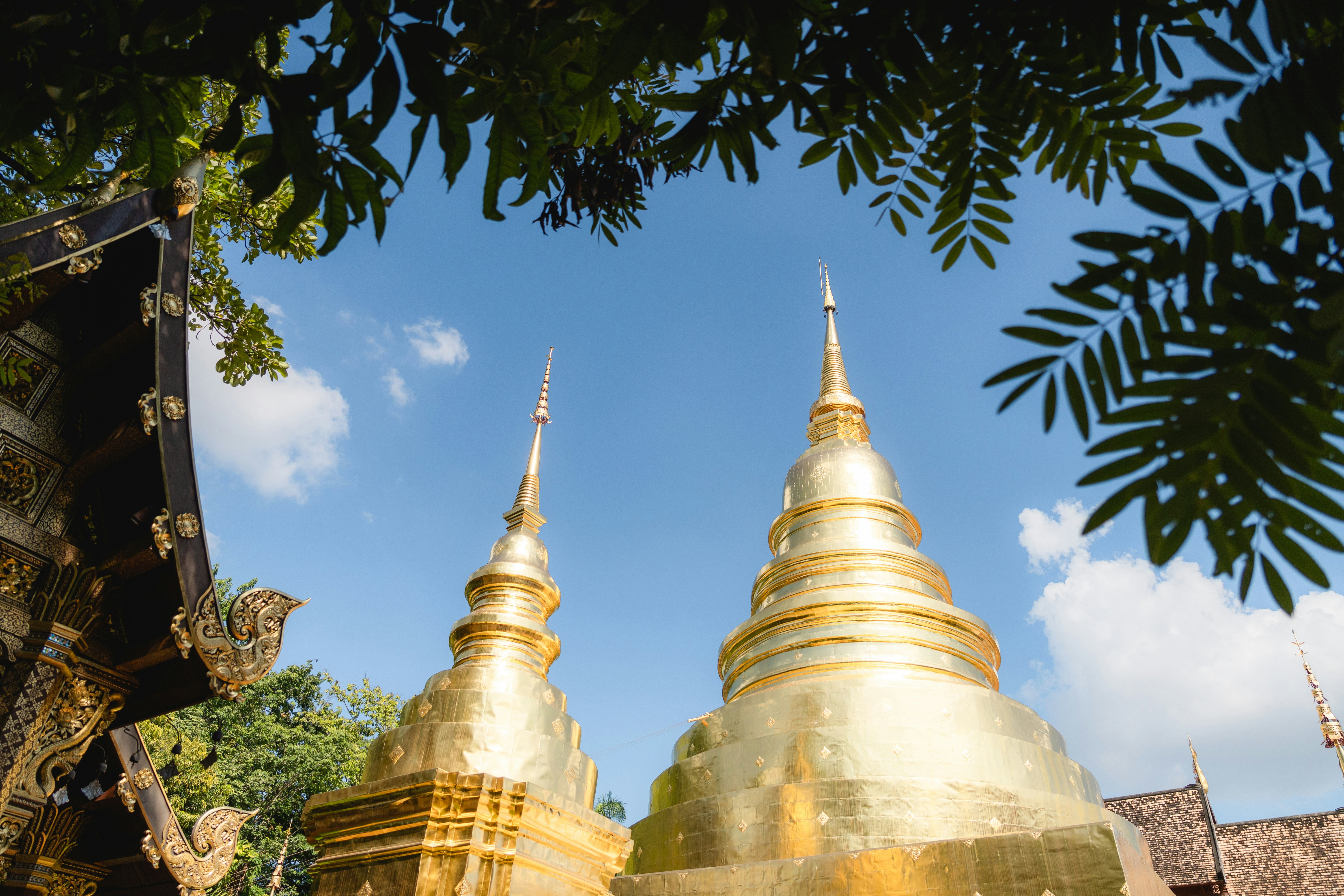 Two golden stupas against a bright blue sky.