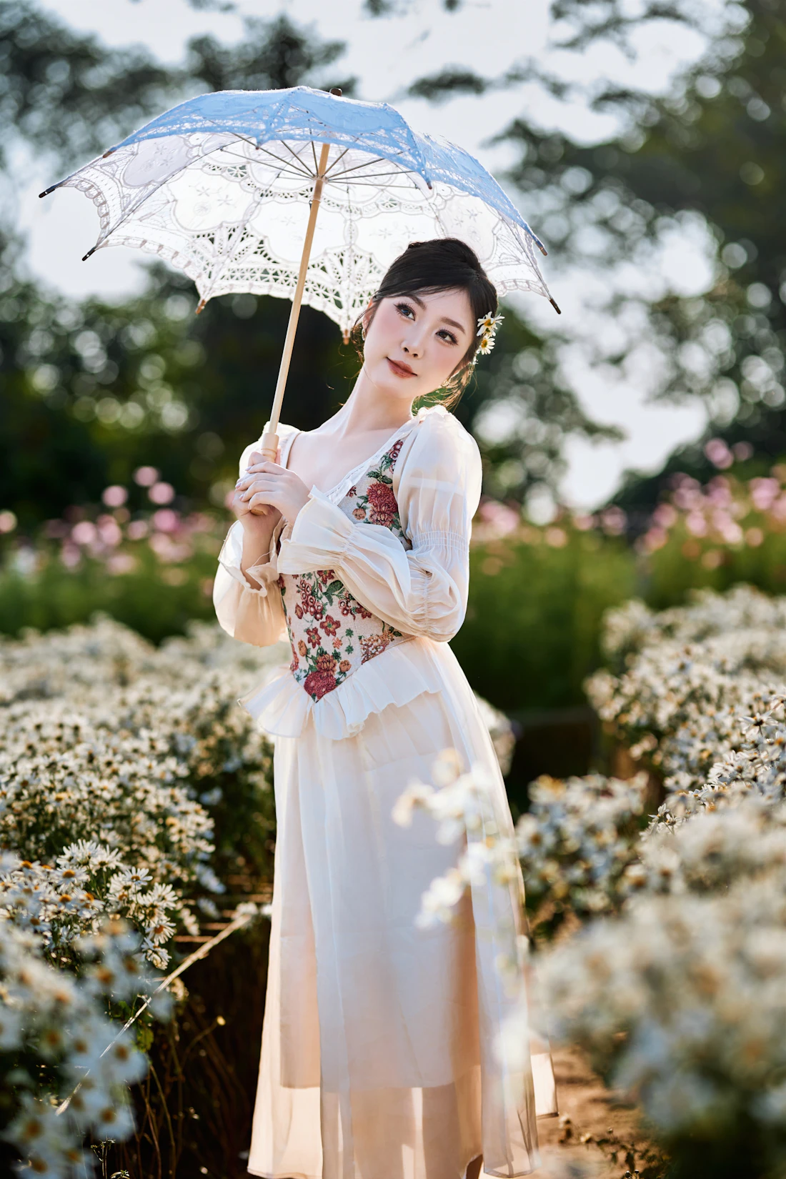 Model in white lace with a parasol among white blossom