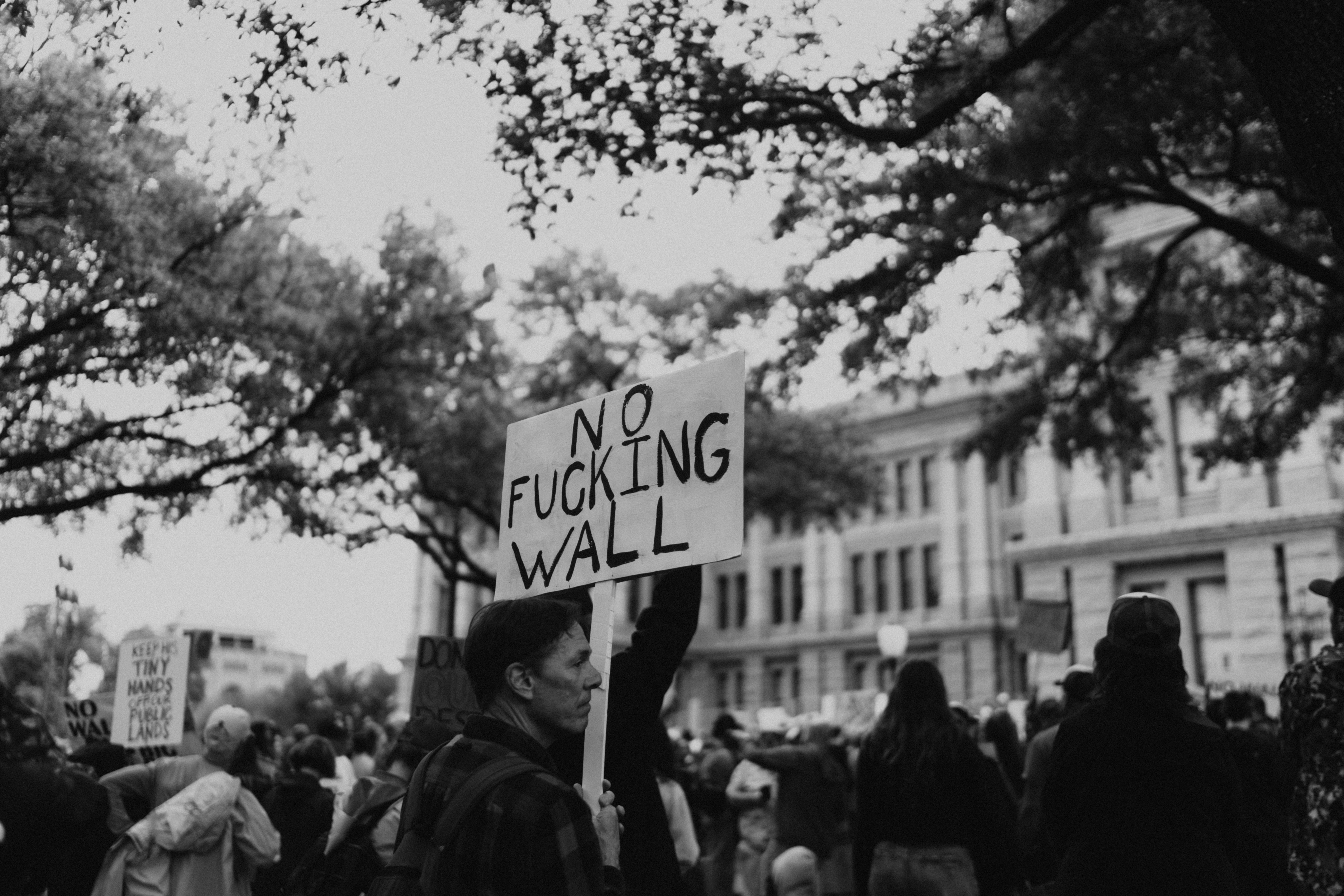 Manifestante sostiene un cartel que dice "no puto muro"