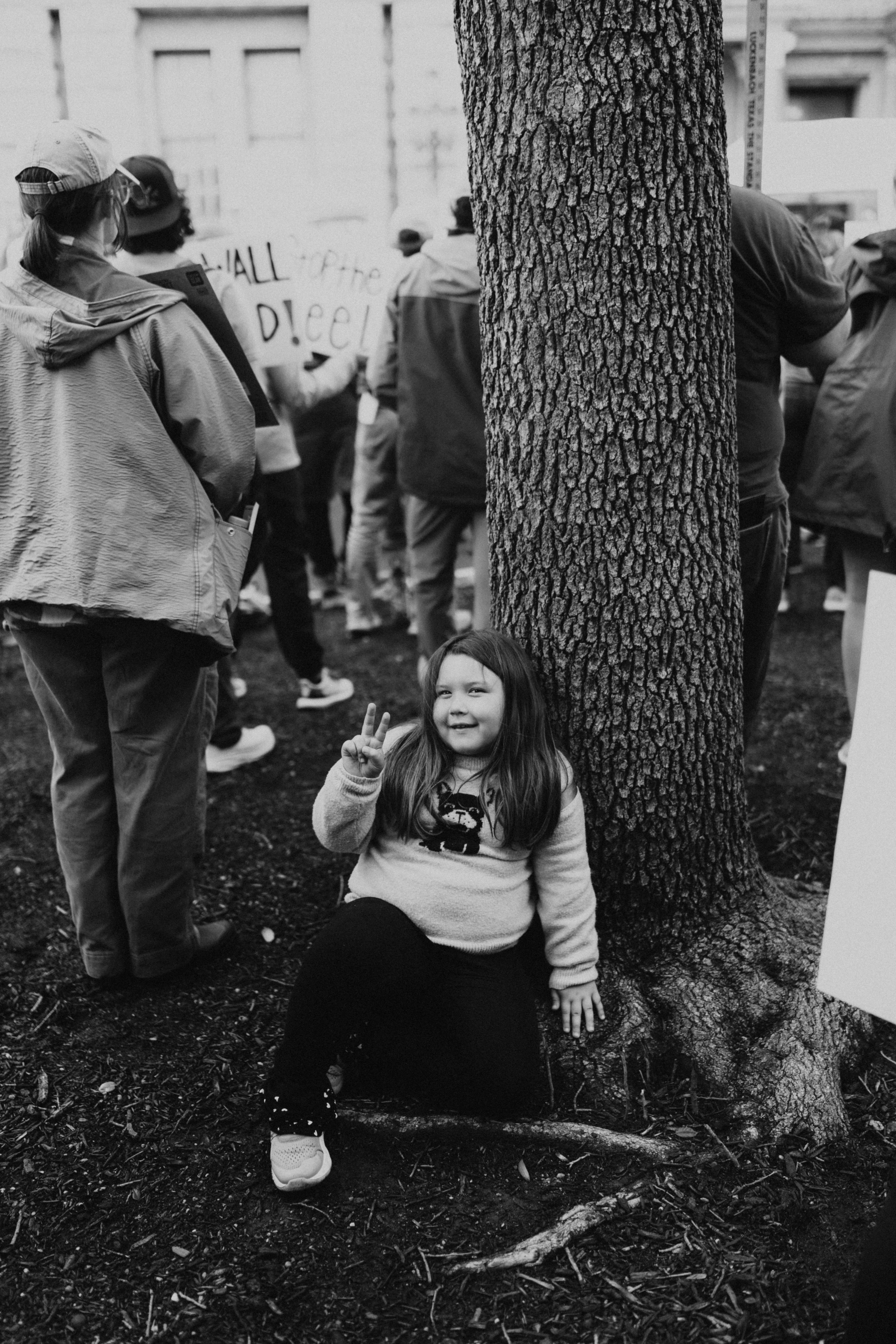 Una joven se sienta junto a un árbol en una manifestación.