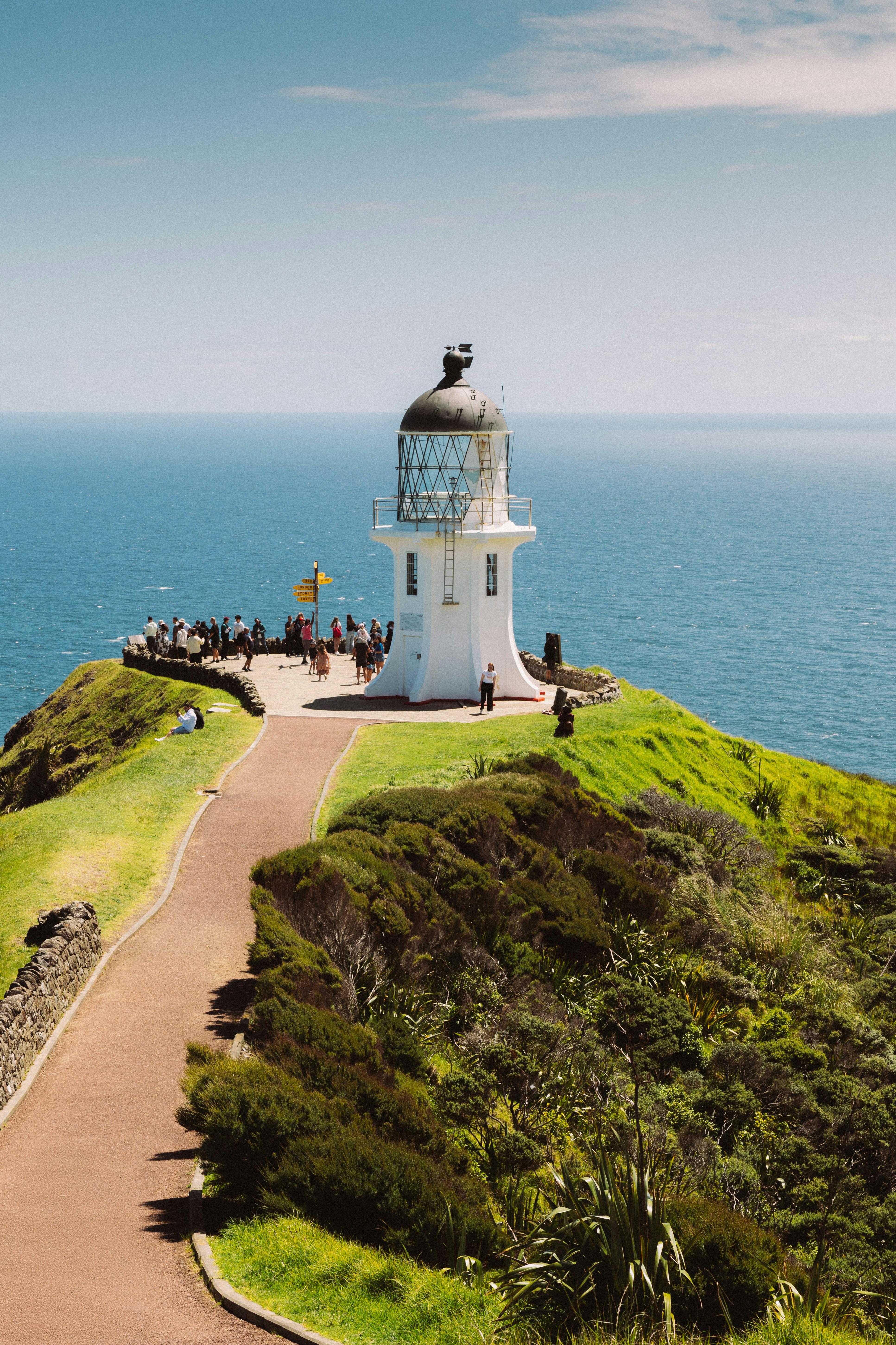 White lighthouse on a grassy hill overlooking the ocean