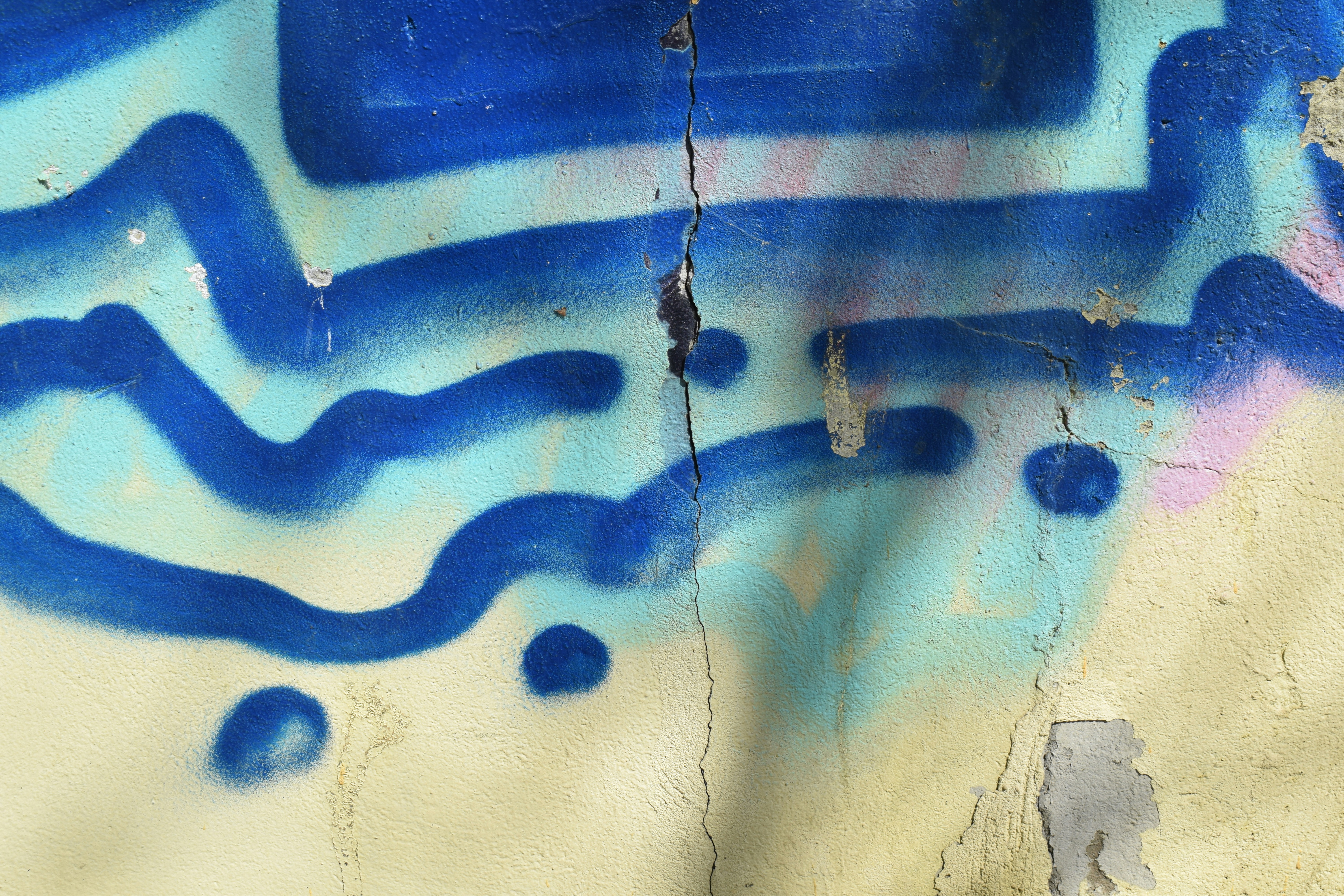 Pared agrietada con arte abstracto azul de graffiti