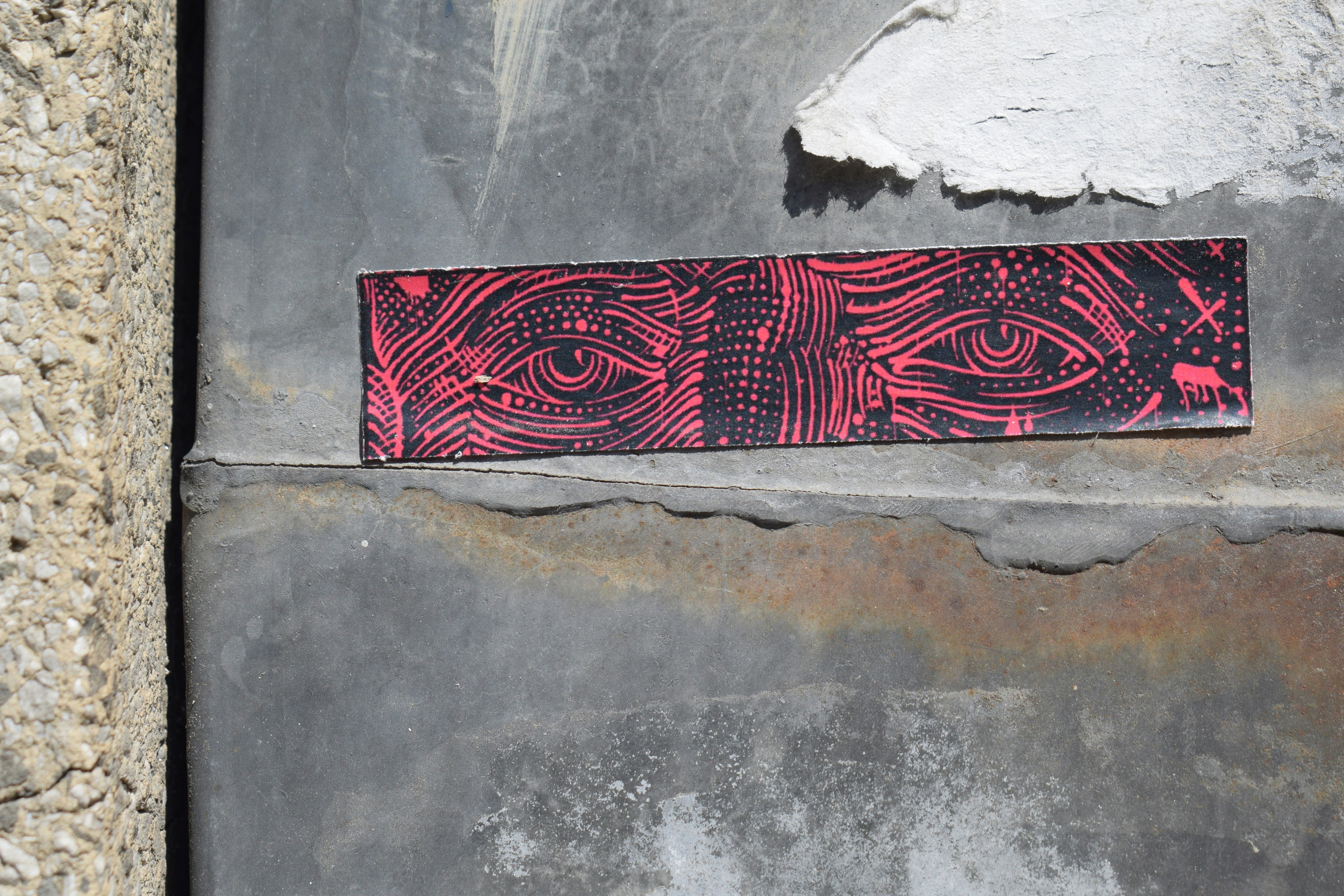 Pegatina de ojos abstractos rojos en una pared texturizada