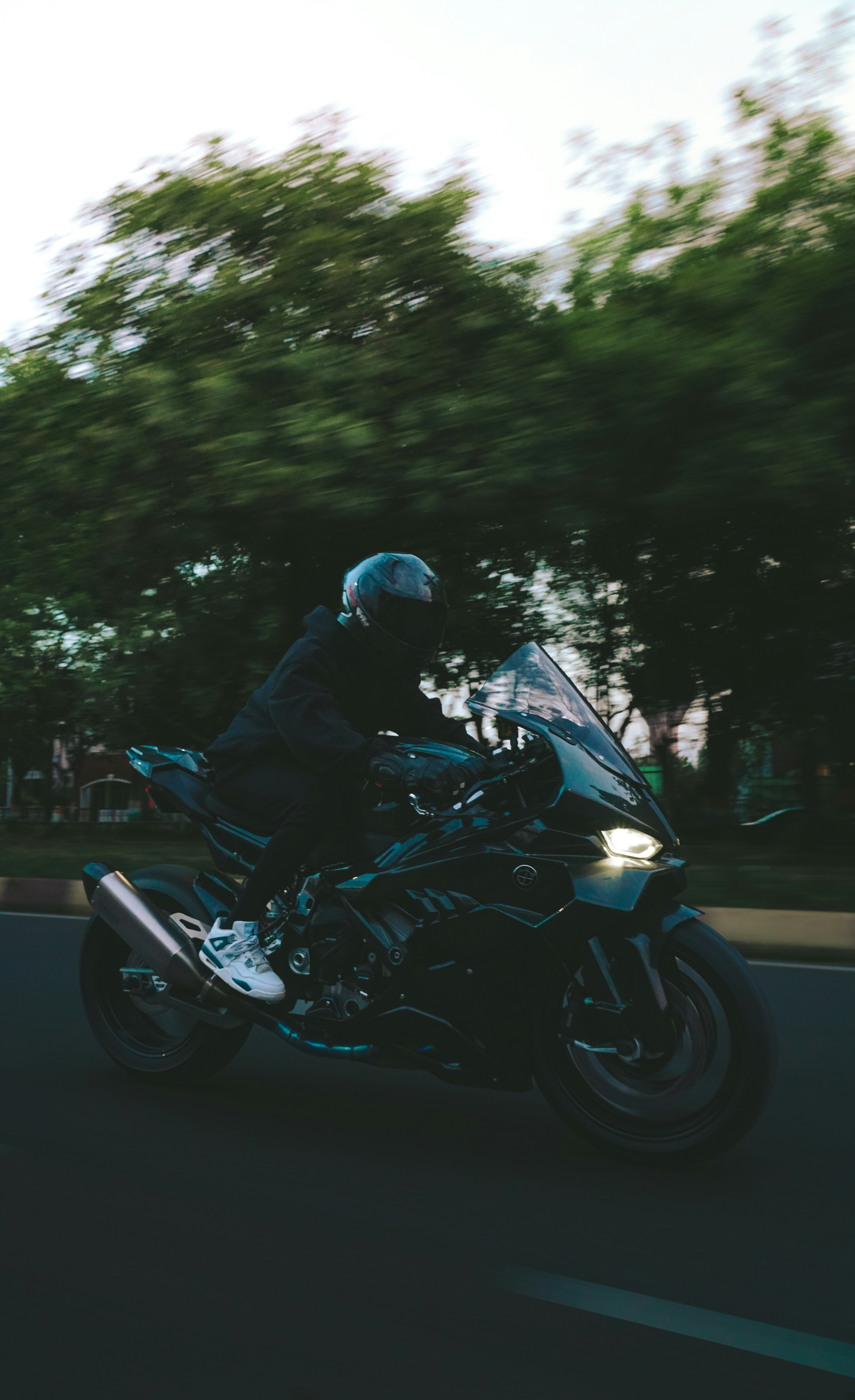 Uma pessoa pilotando uma moto escura em uma estrada.