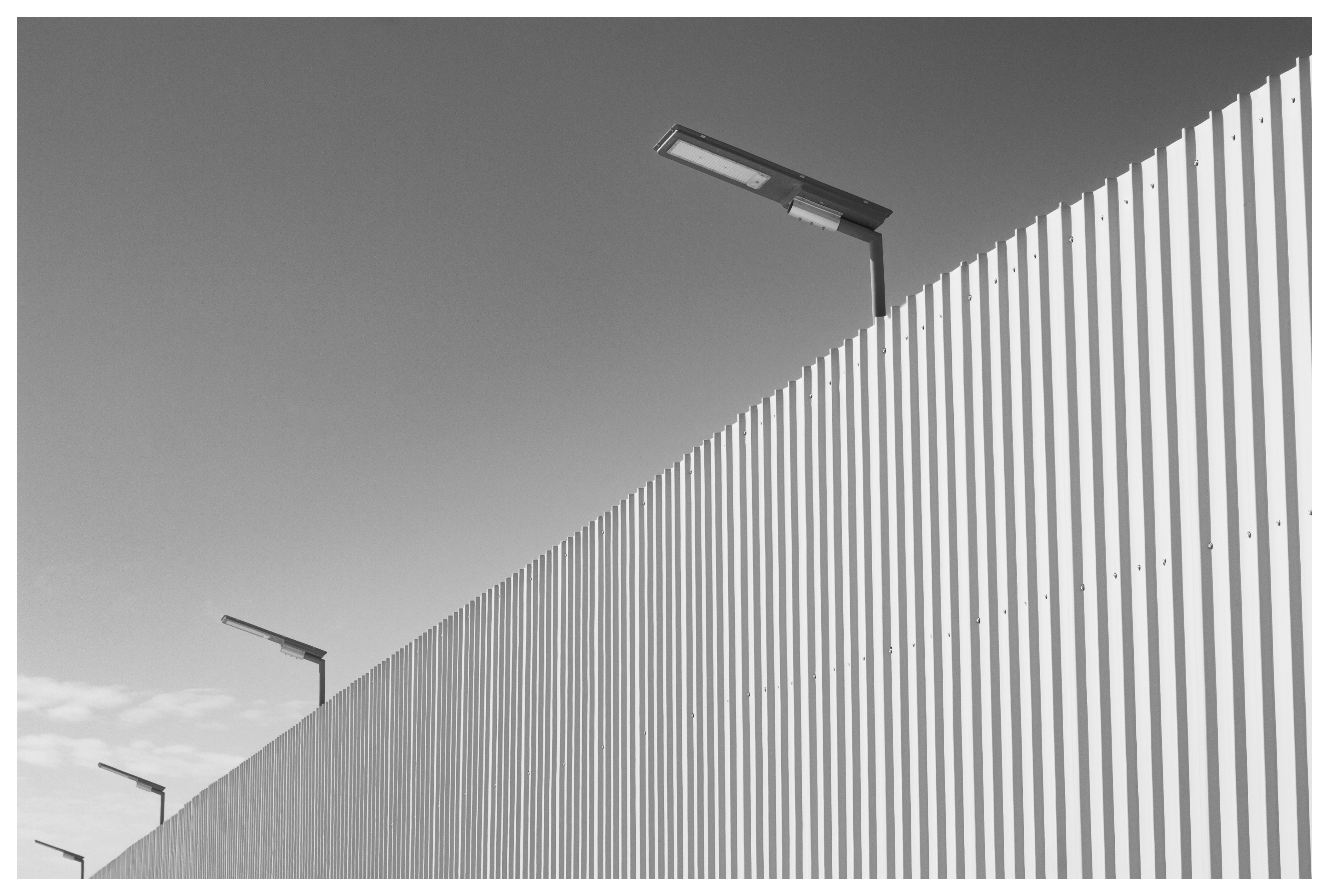 Streetlights on a corrugated metal fence