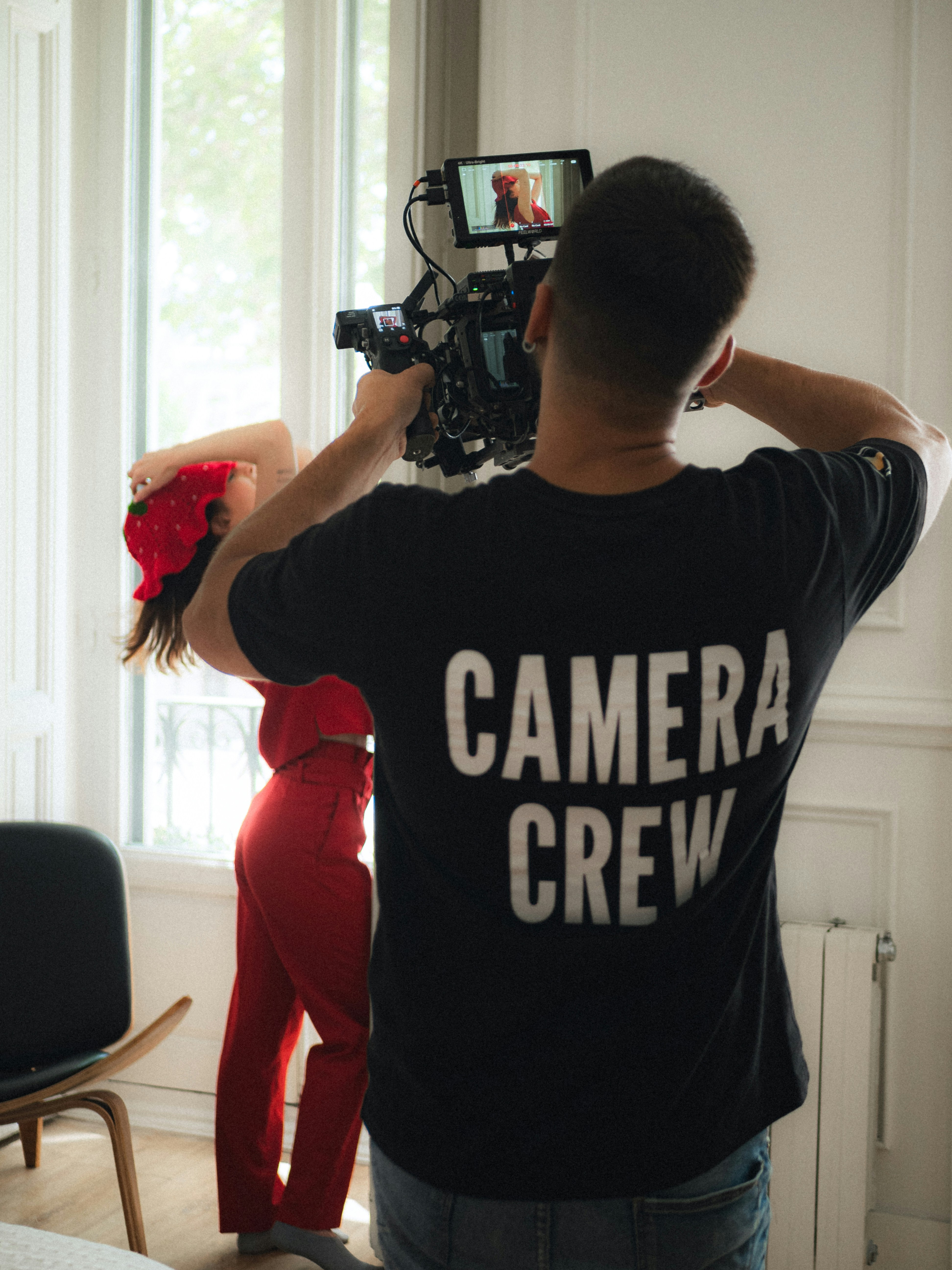 Camera crew filming a woman in red attire