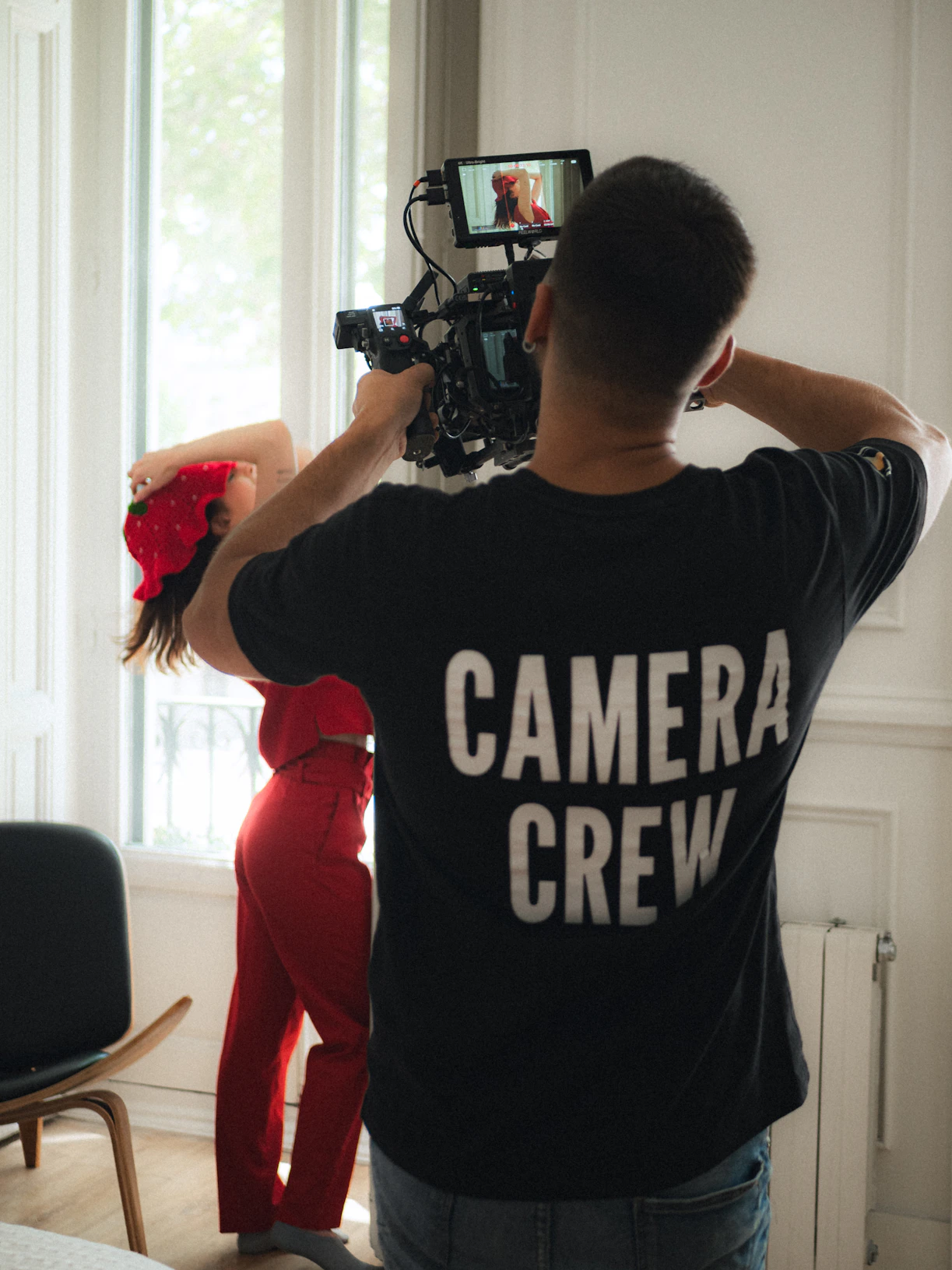 Camera crew filming a woman in red attire
