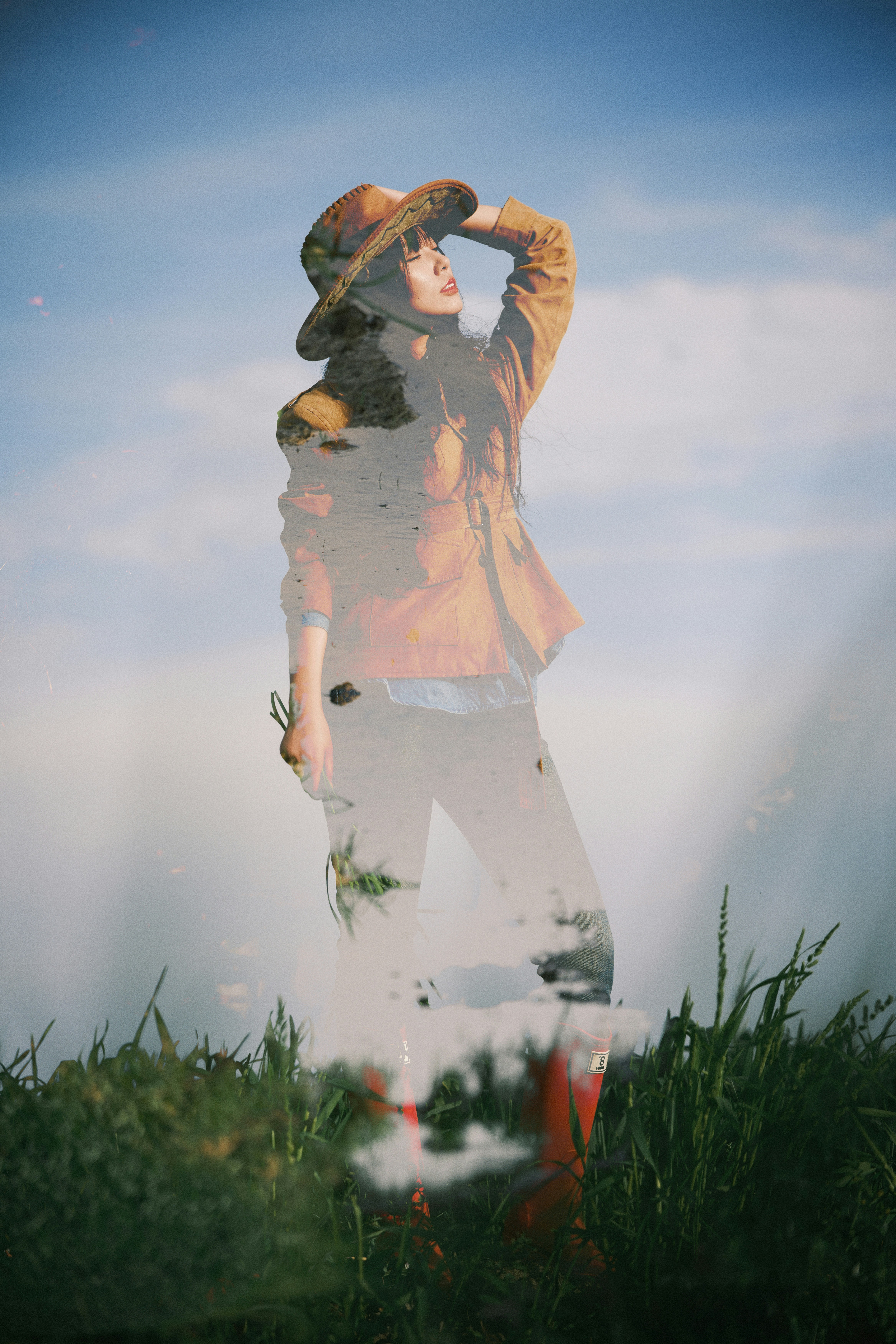 Woman in hat and jacket stands in grass