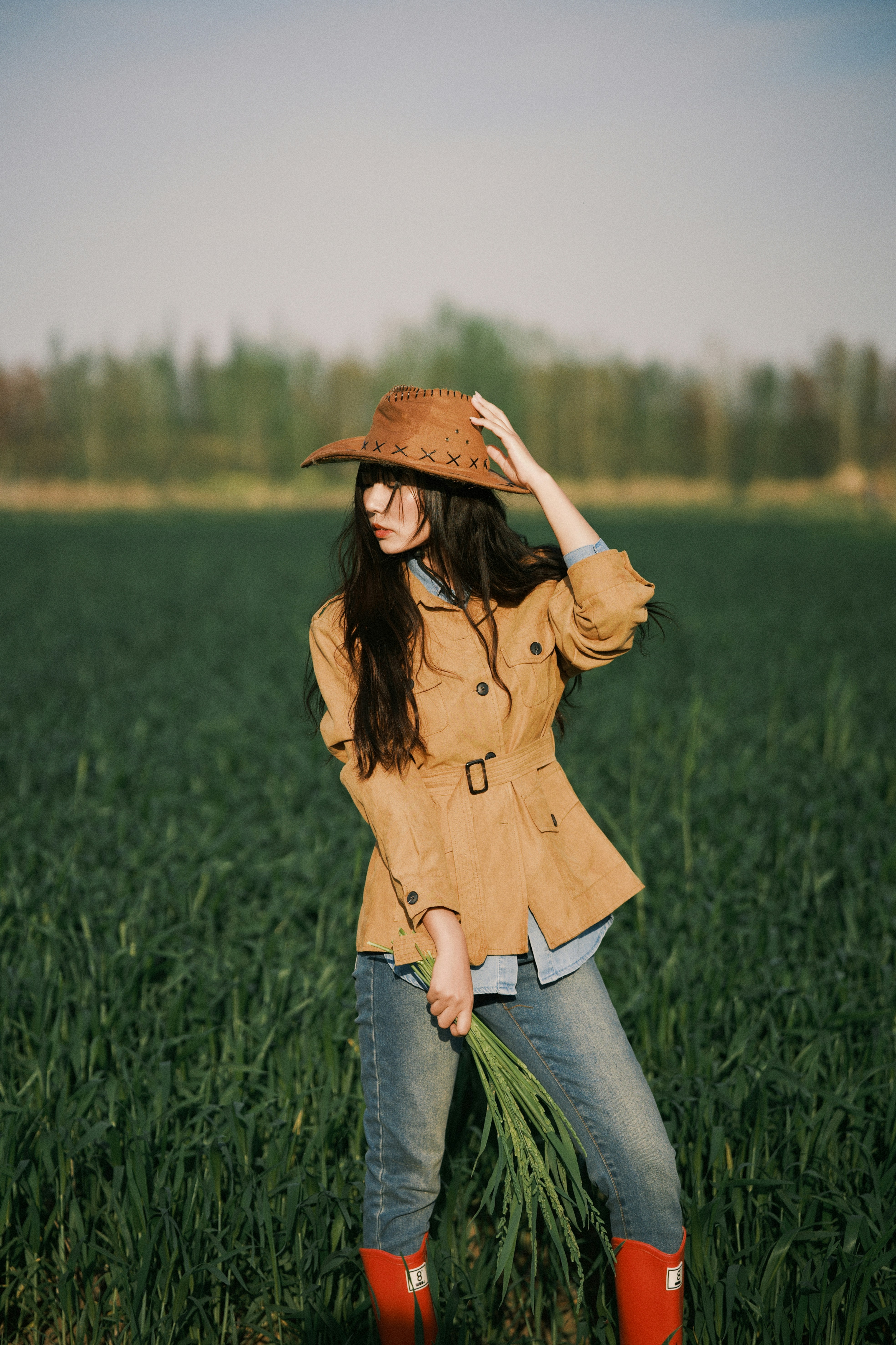 Woman in cowboy hat in a green field