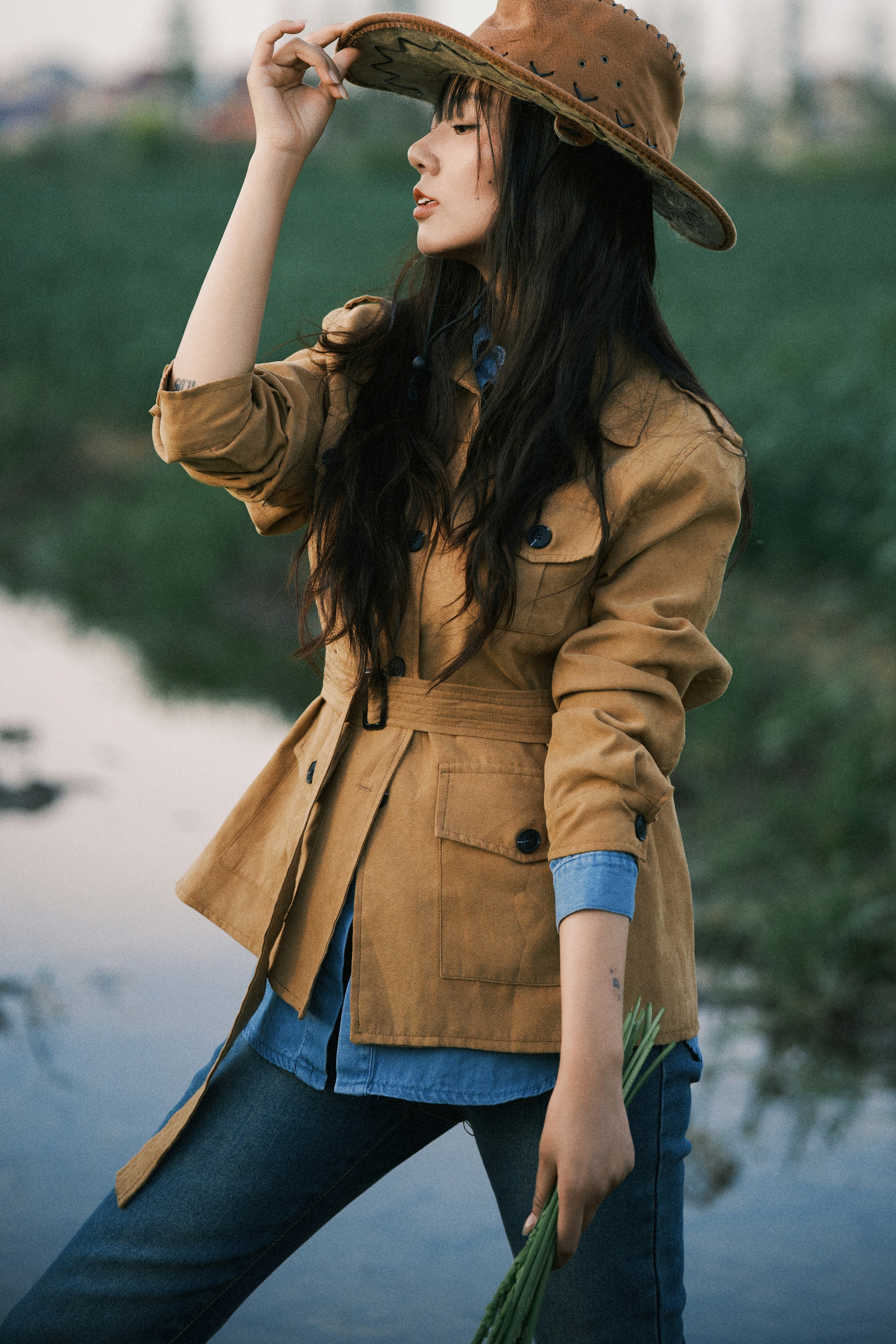Woman in safari outfit adjusting her hat in a field