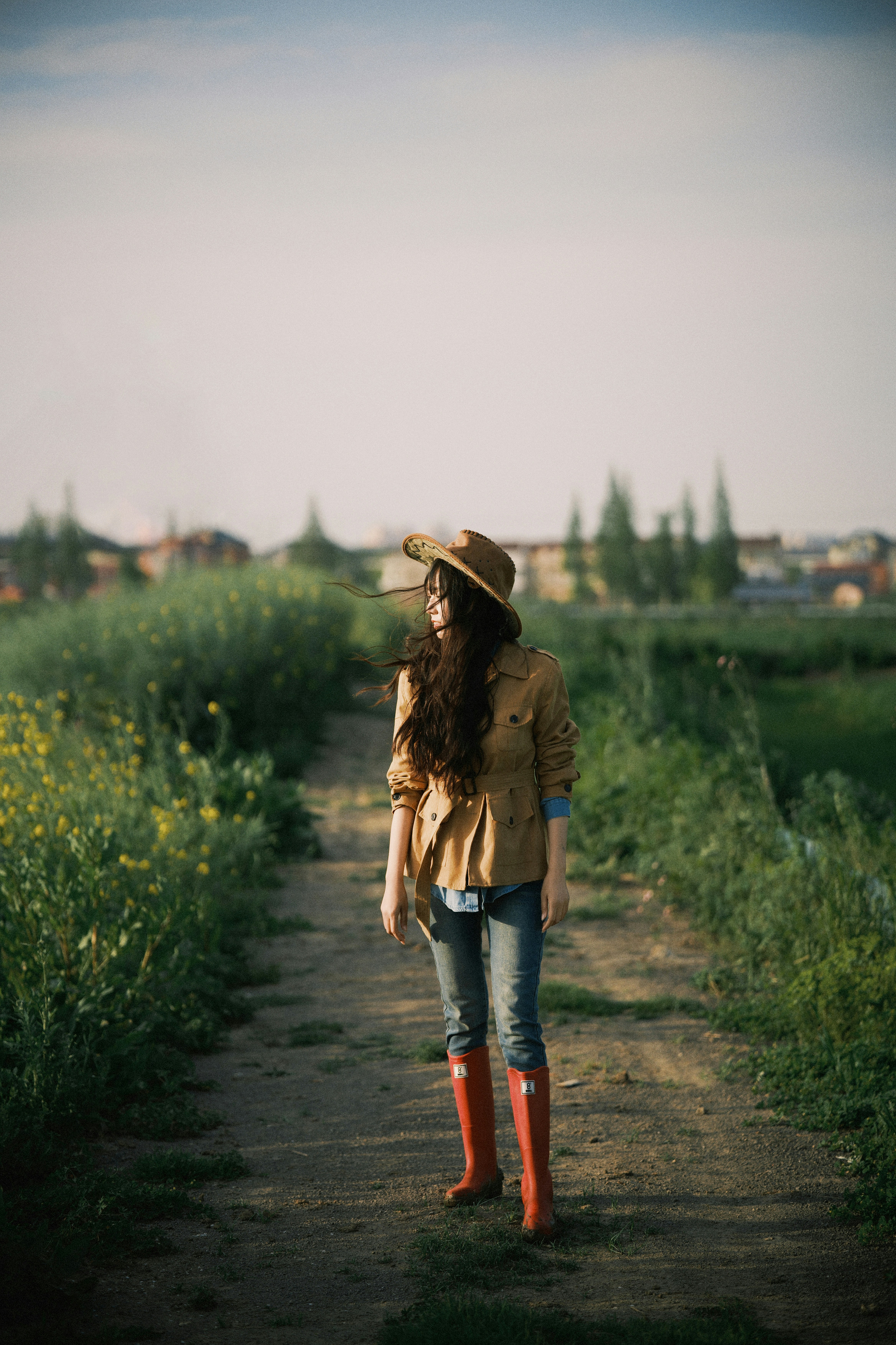 Woman in cowboy hat and red boots on dirt path
