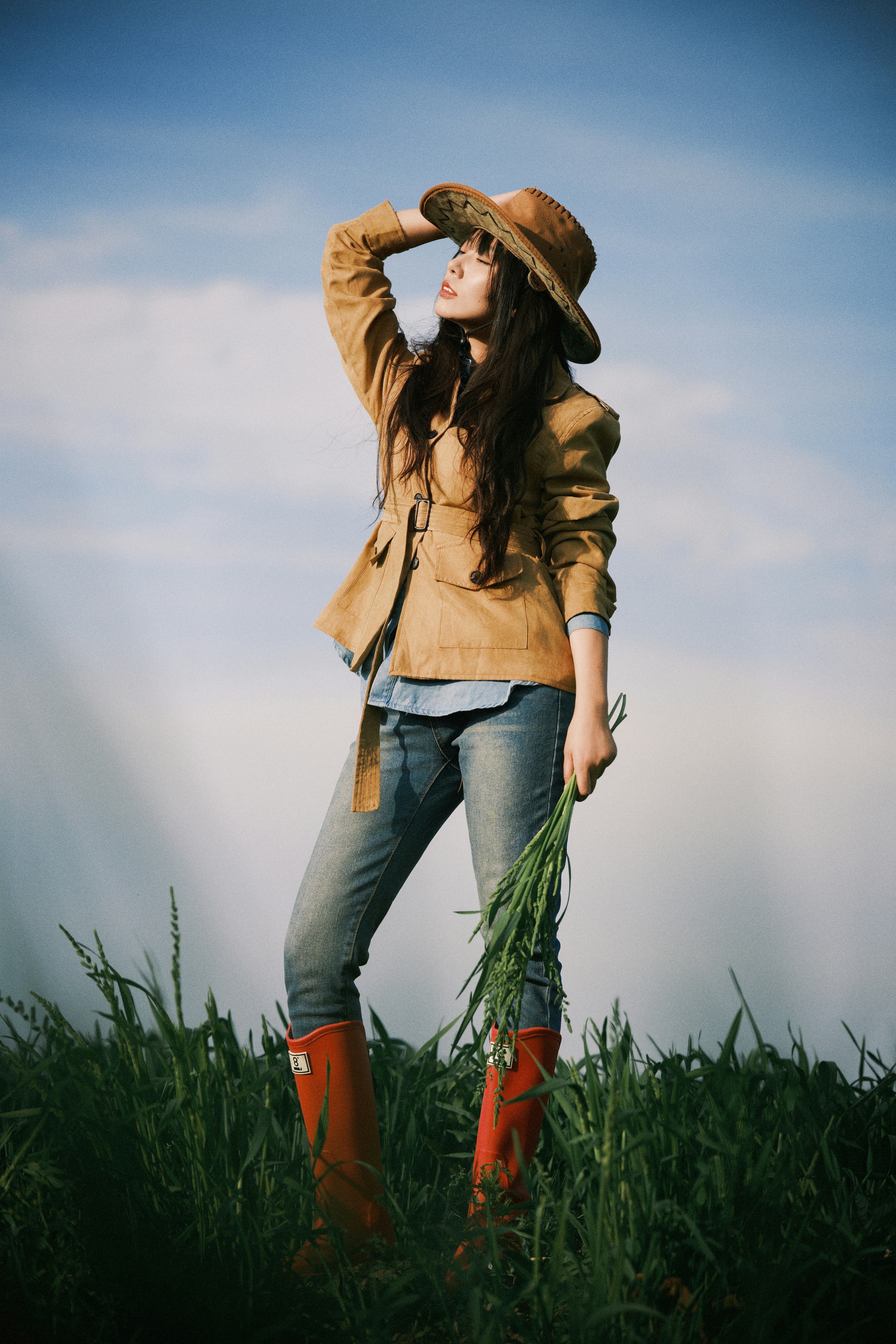 Woman in hat and boots in a grassy field