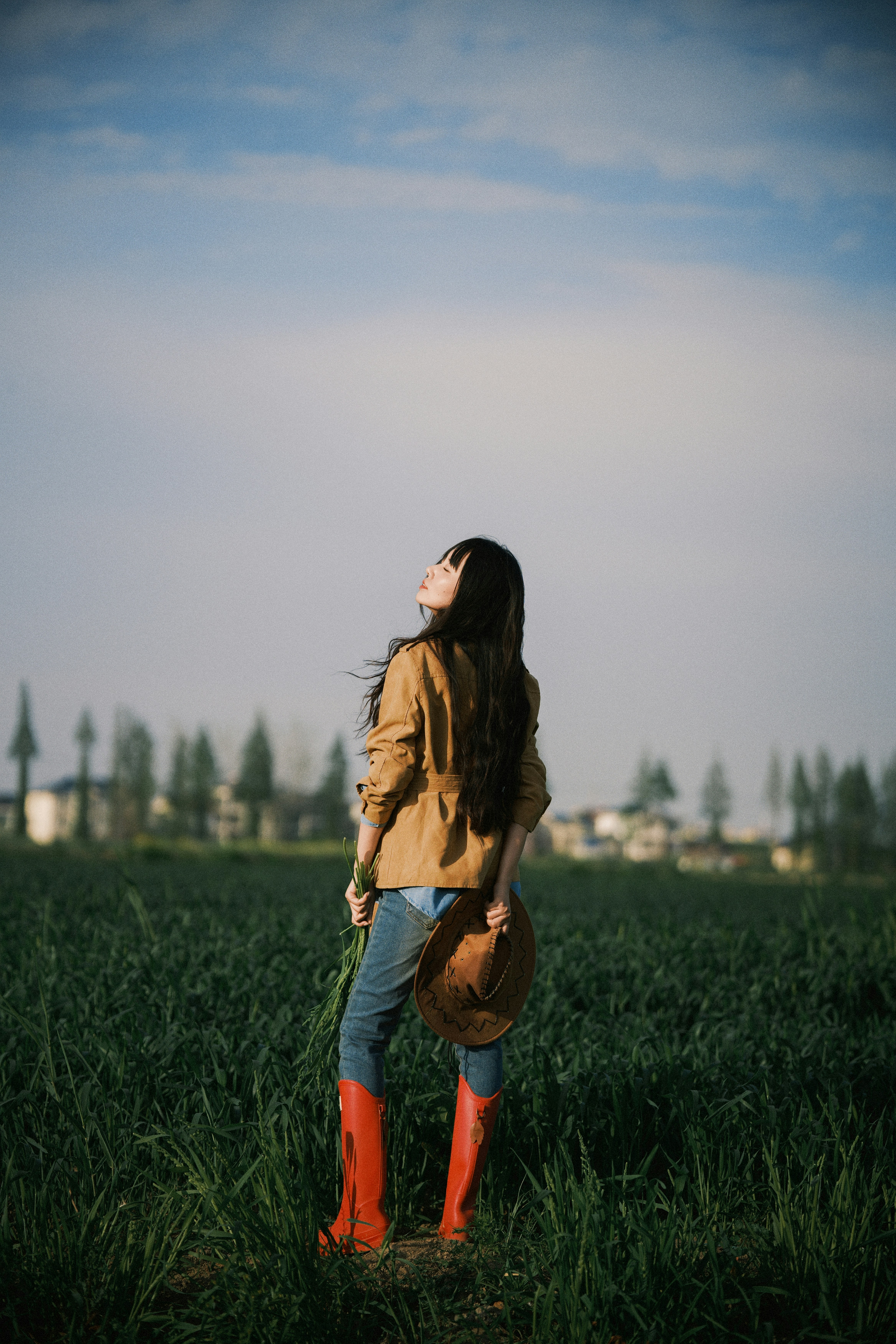 Woman in red boots holding hat in field