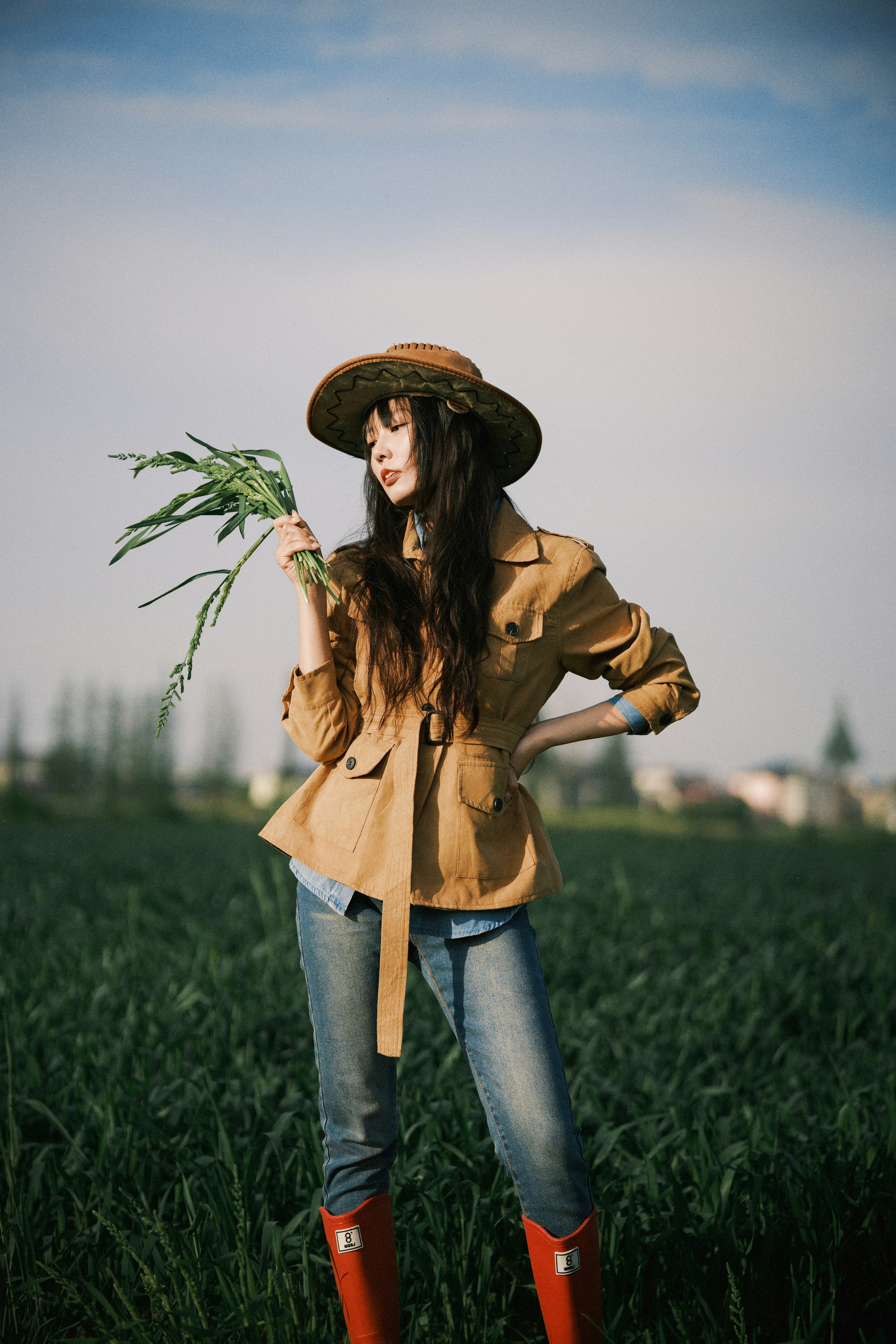 Woman in hat holding wheat in a field