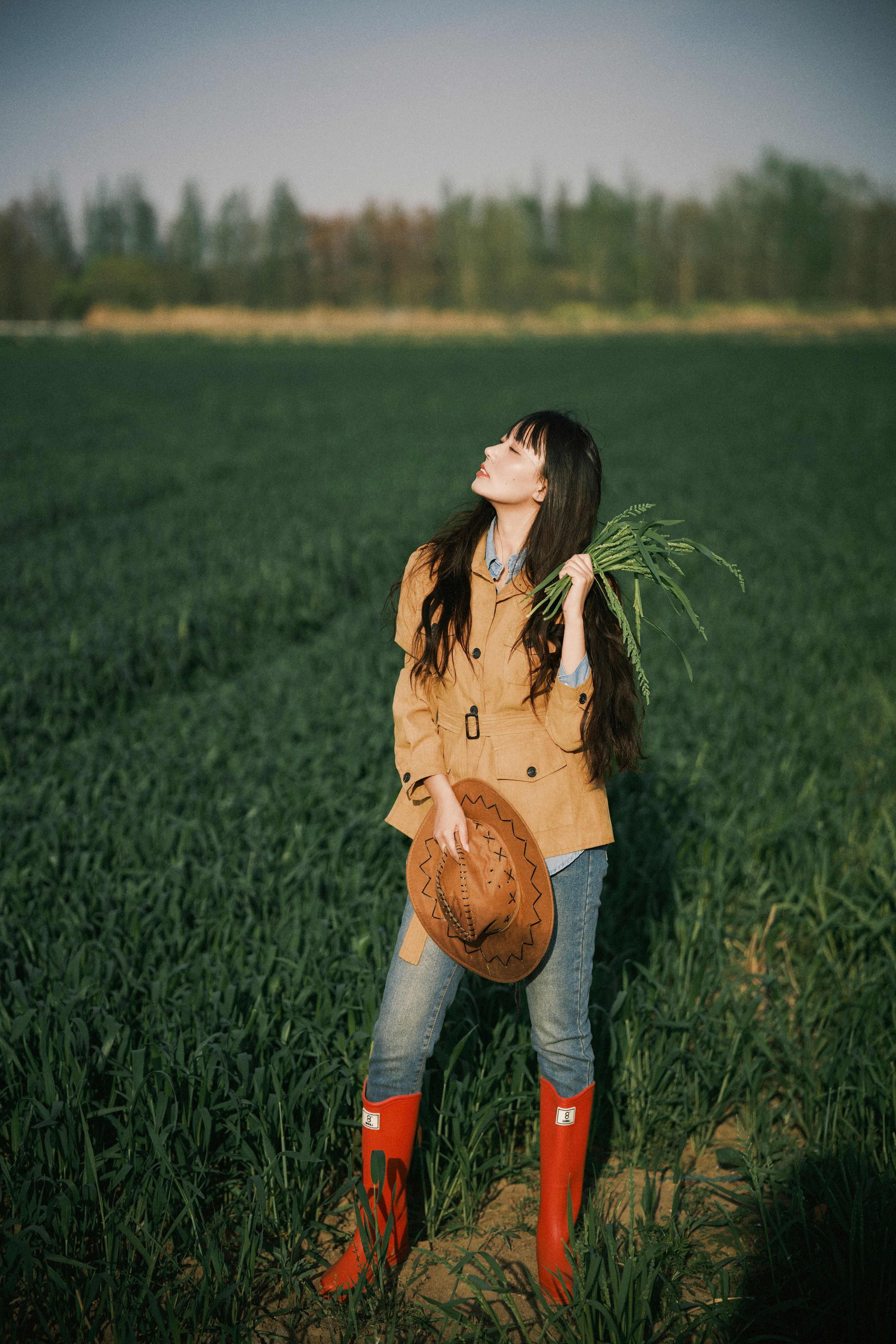 Woman in cowboy hat and red boots in a field